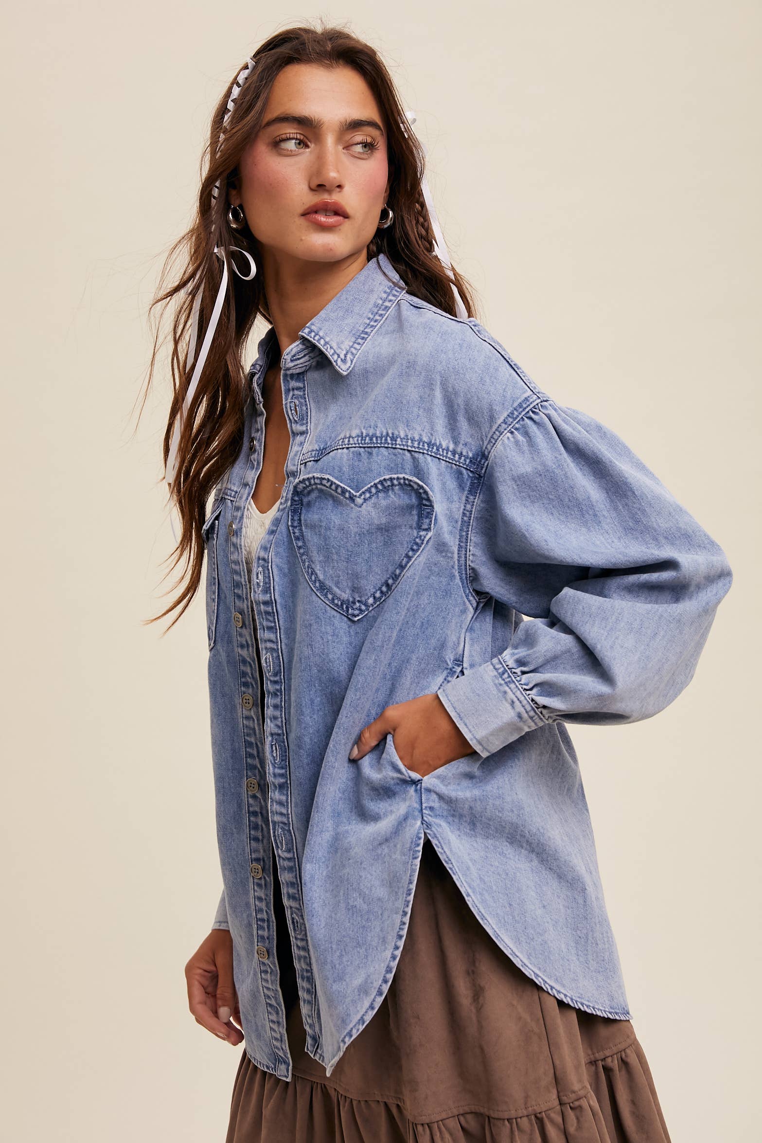 Side view- Light-wash oversized denim shacket with a heart-shaped chest pocket, button front, drop shoulders, balloon sleeves, and a curved hem.