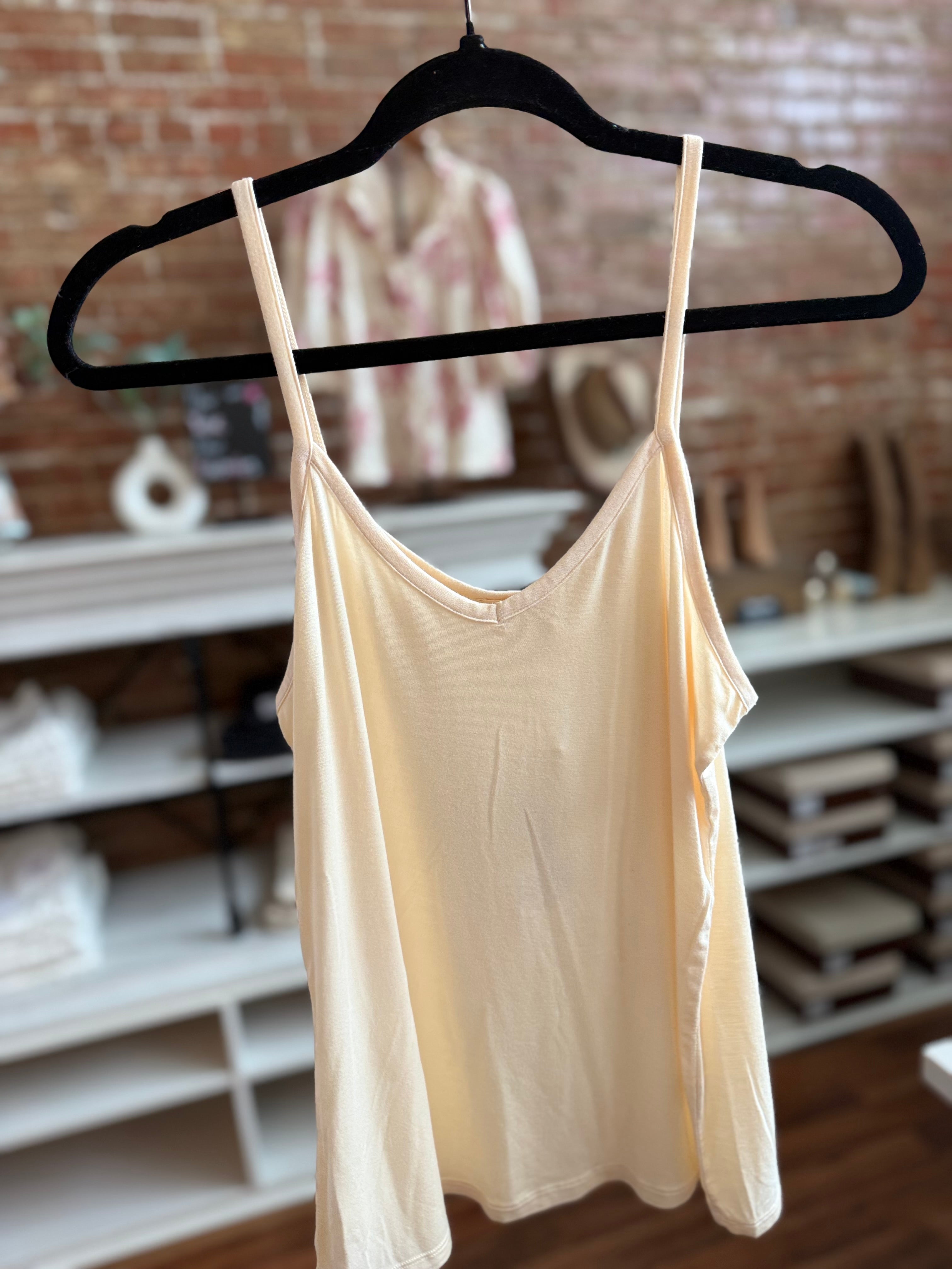 Beige tank top on a hanger against a brick wall background