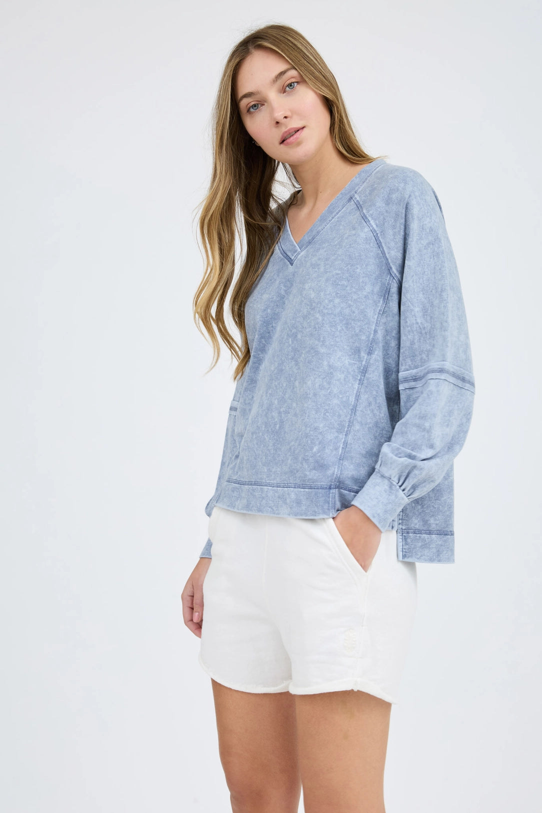 Woman wearing a blue sweater and white shorts on a white background