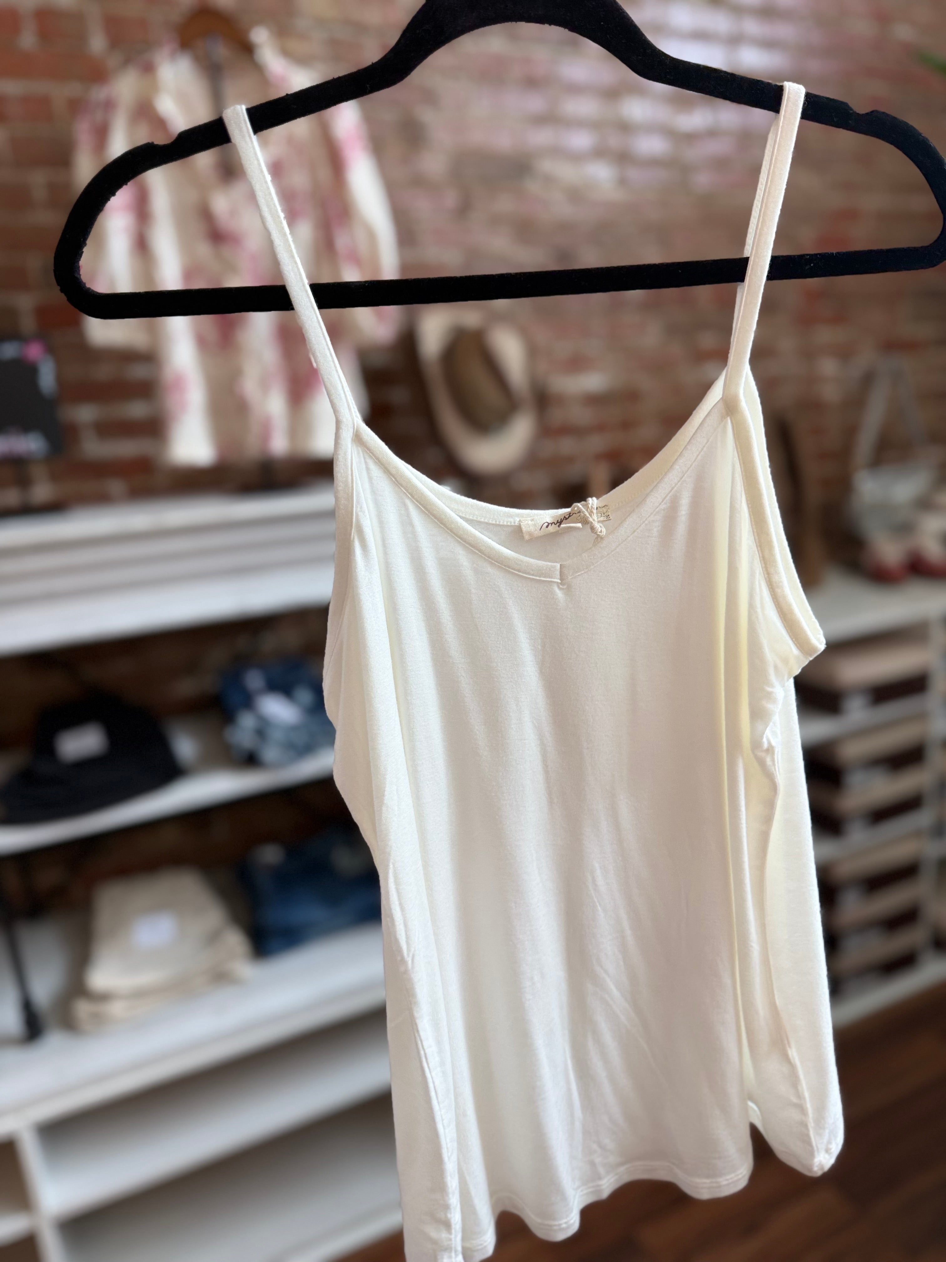 White tank top on a black hanger against a brick wall background