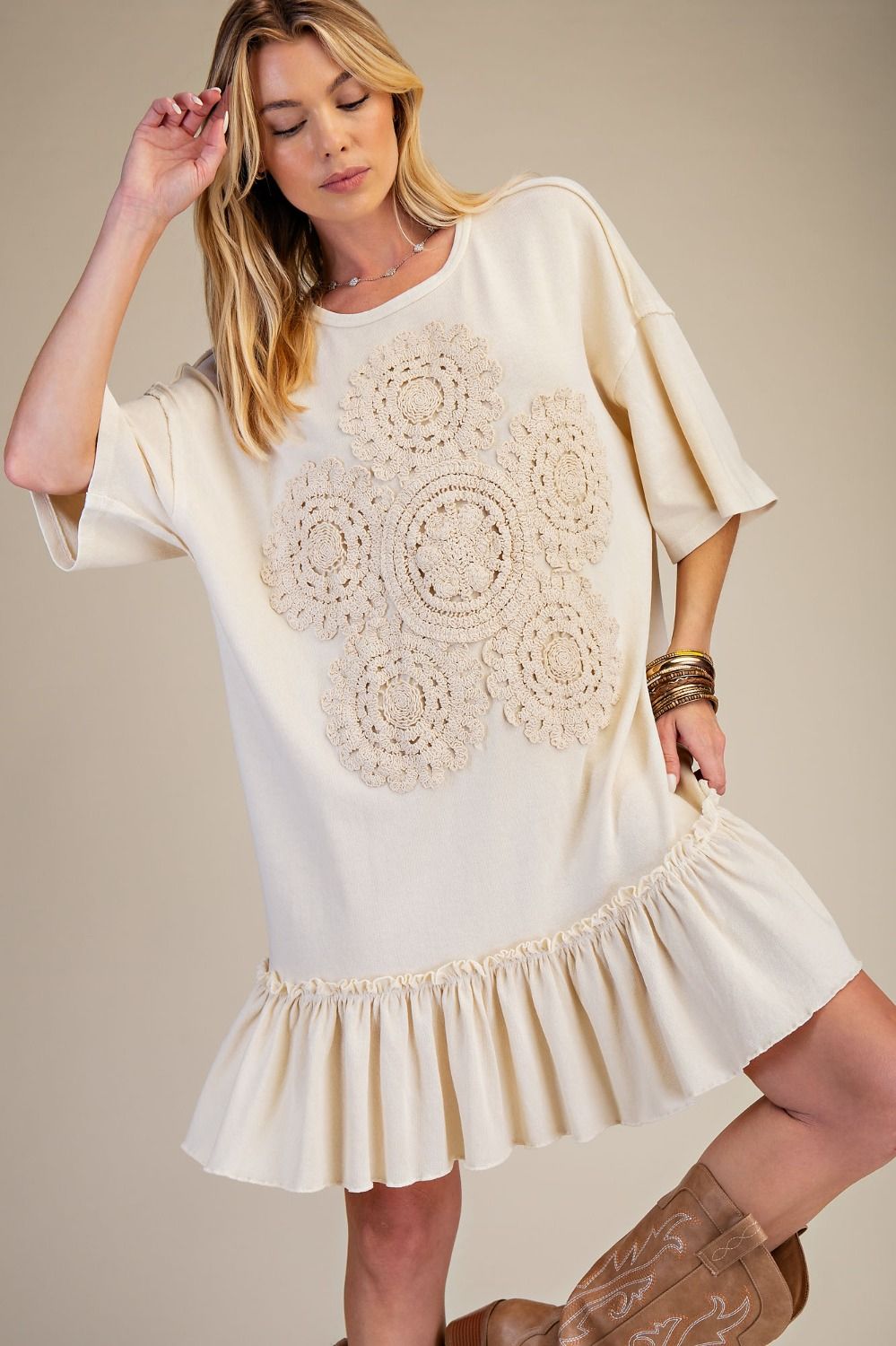 Woman wearing a white dress with crochet details on a beige background