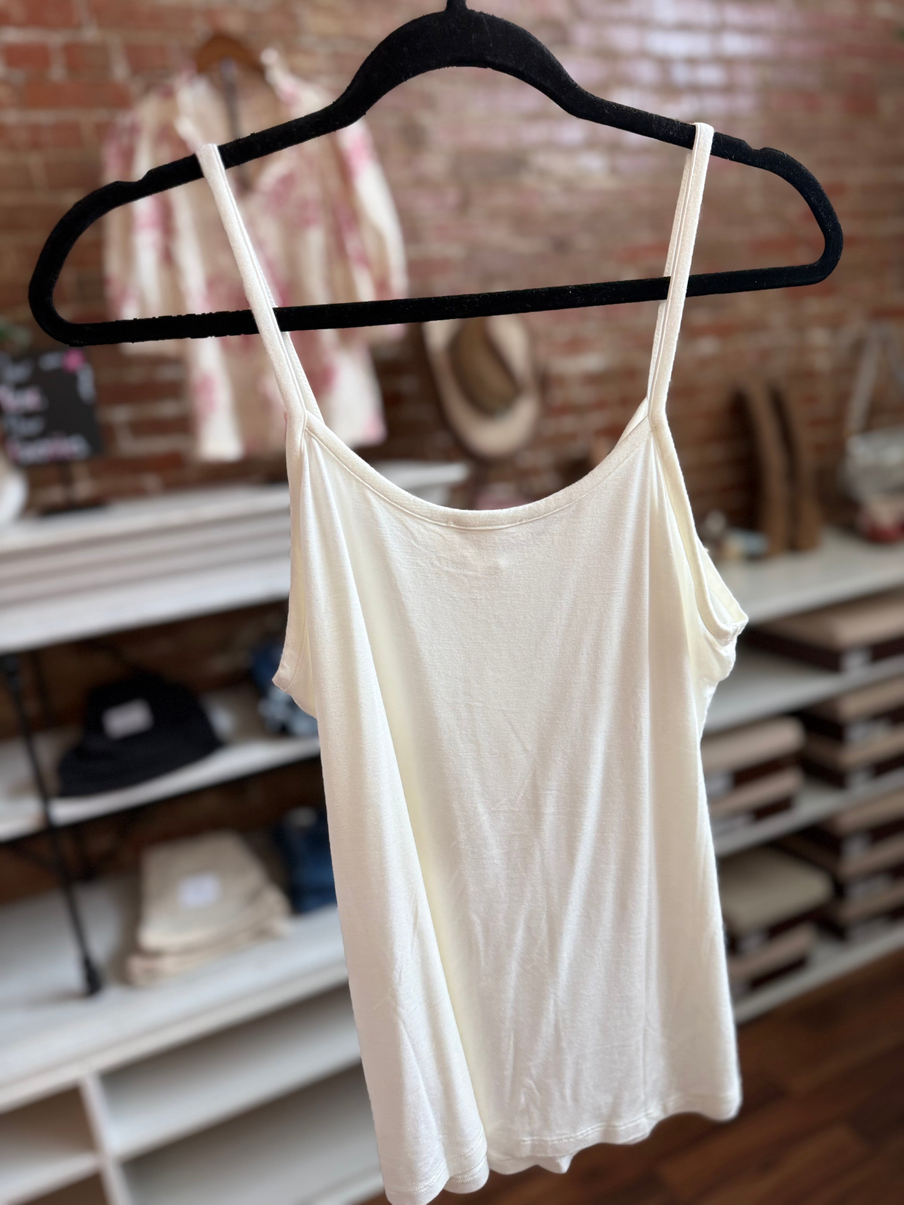 White tank top on a black hanger against a brick wall background