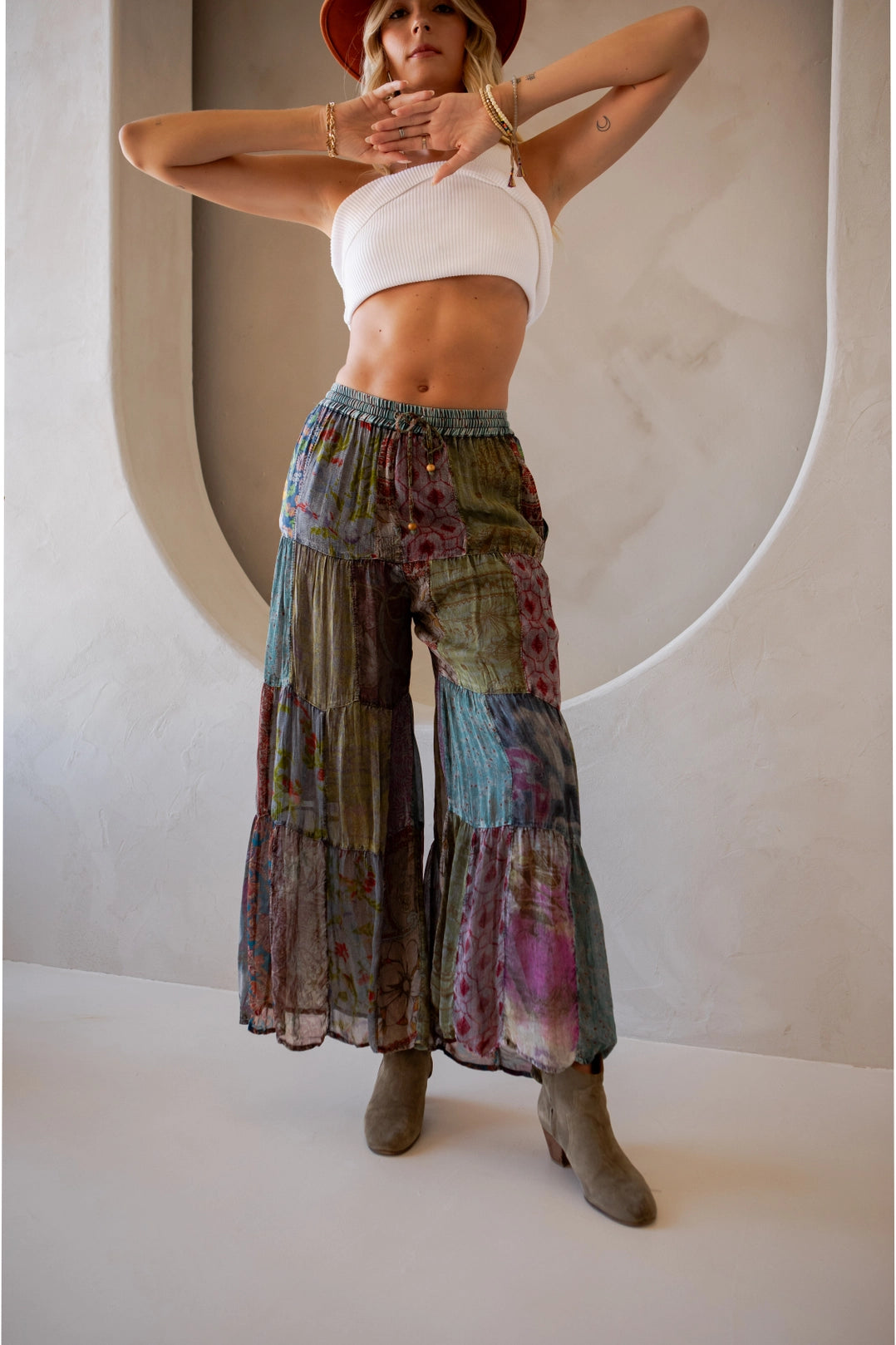 Woman wearing a white top and colorful tiered pants against a neutral background