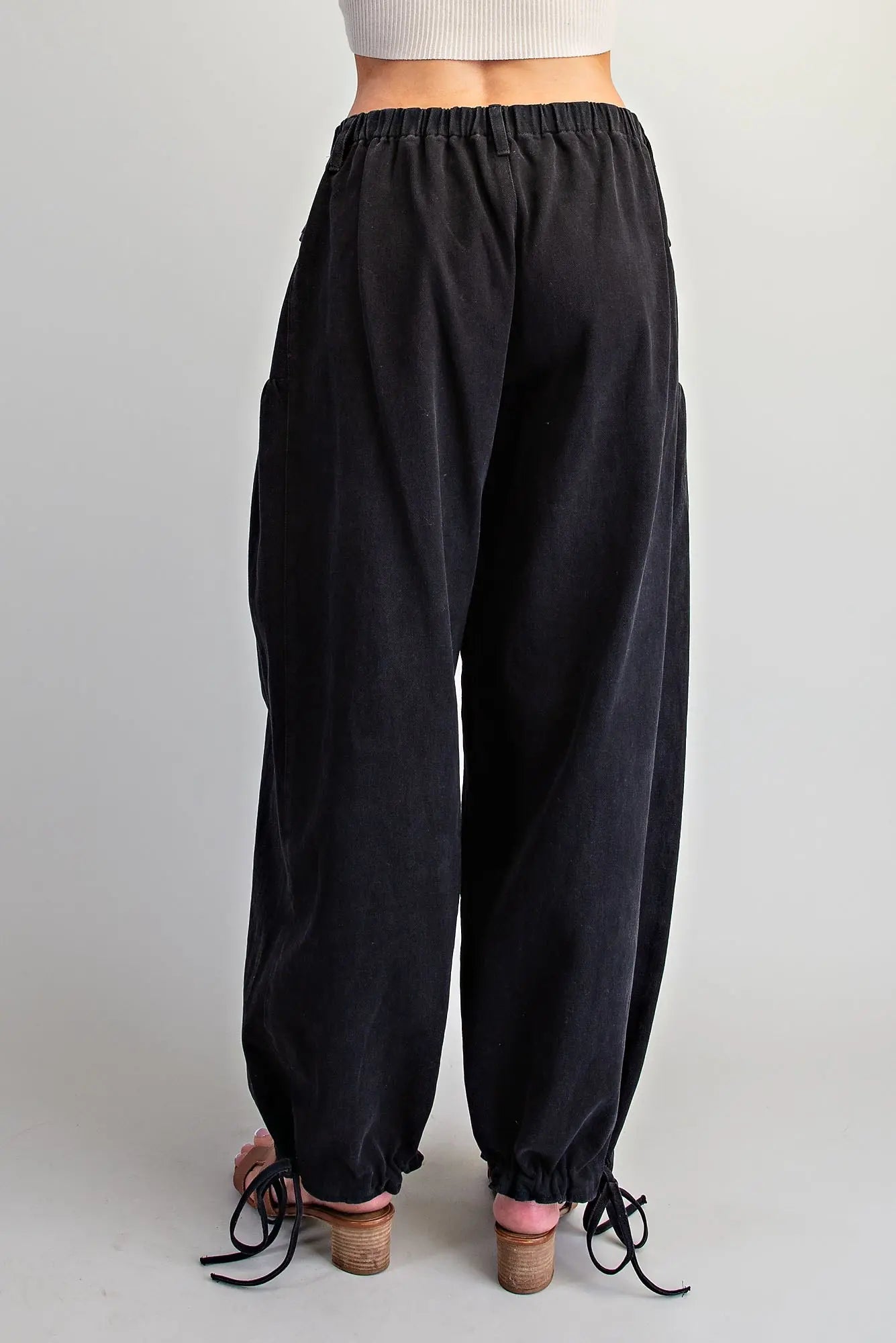 Black wide-leg jogger pants with an elastic waistband and drawstring ankle cuffs, shown from the back on a model against a light gray background.