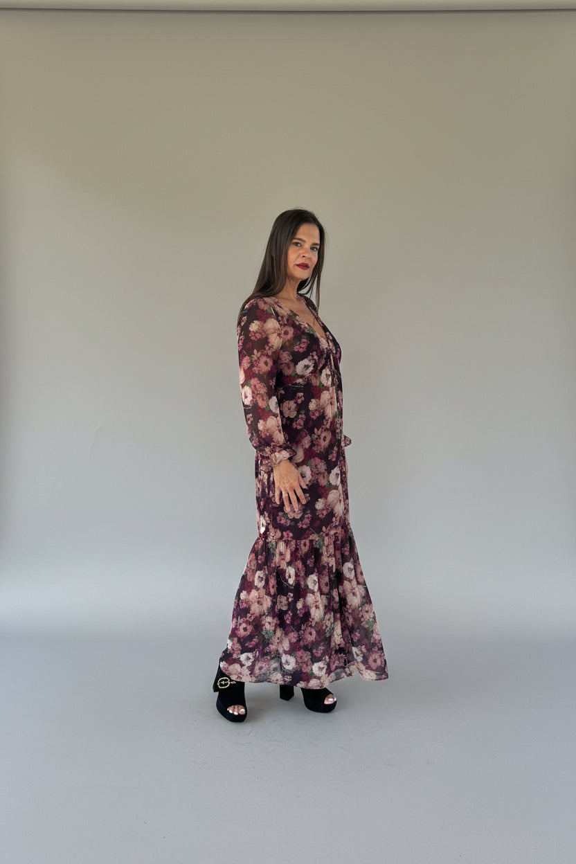 Model posing confidently in burgundy floral long-sleeve maxi dress with hand on hip, full-length view showing flare silhouette