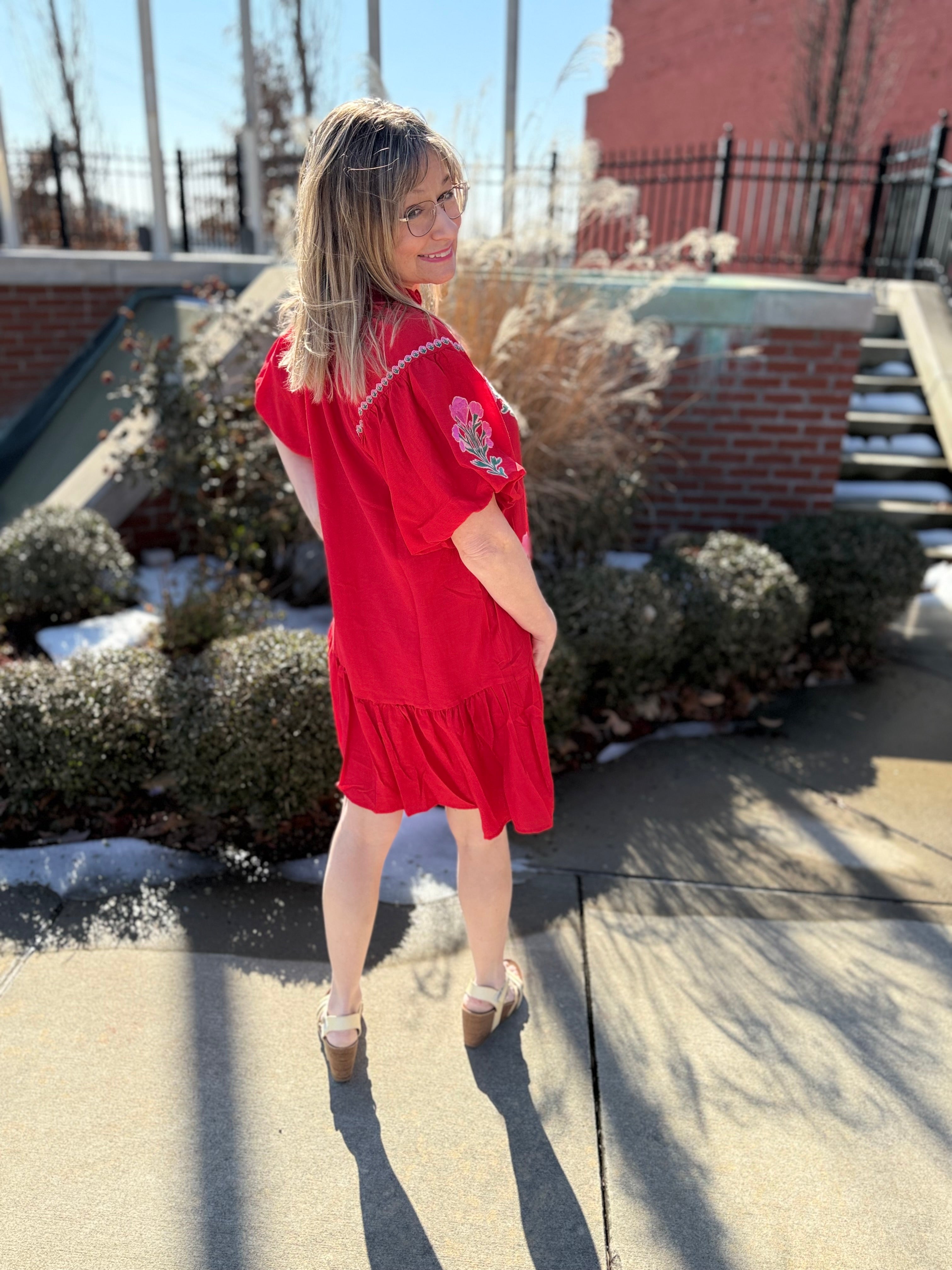 Woman in a red dress standing on a rooftop with snow on the ground