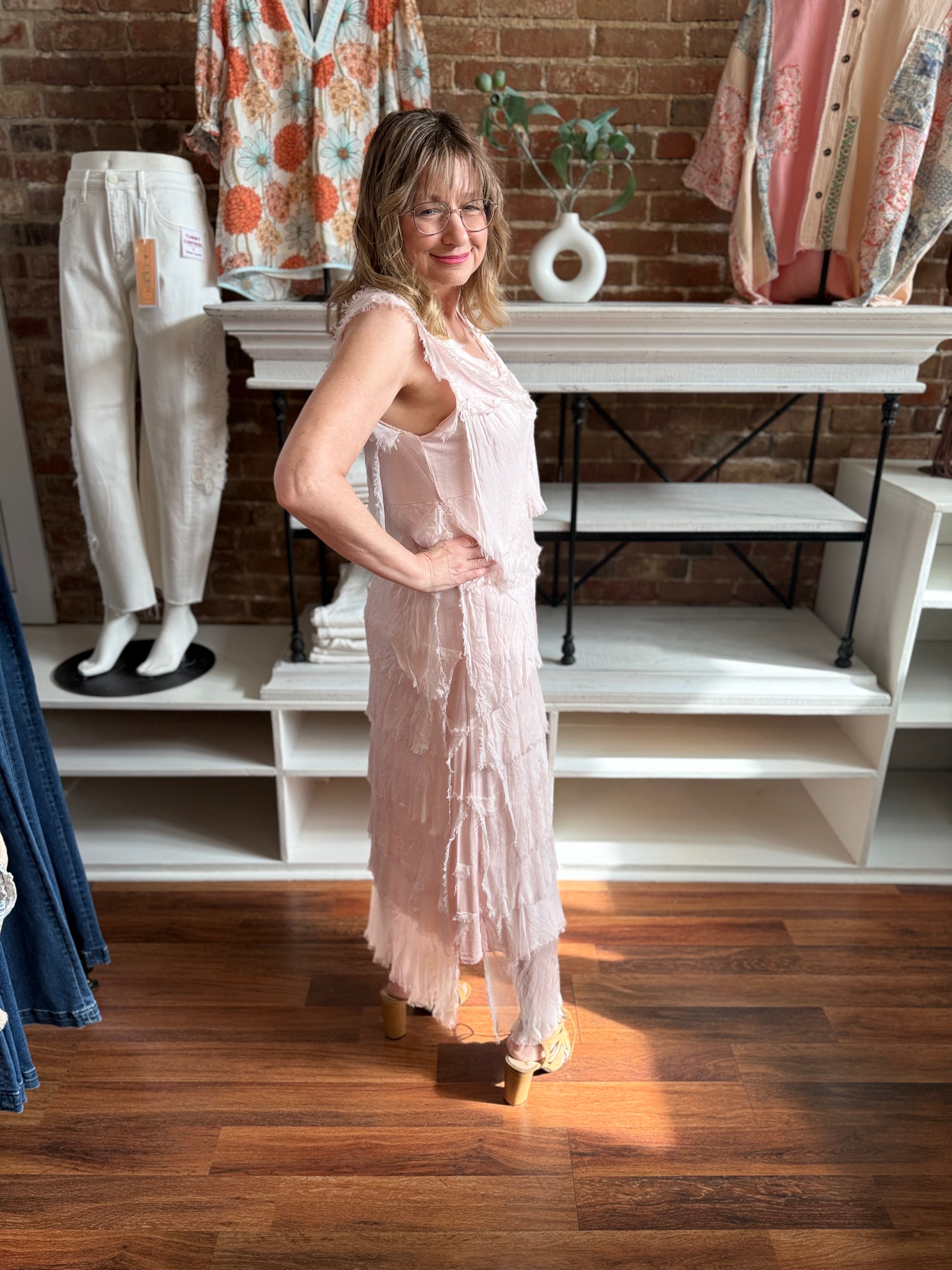 Woman in a pink dress standing in a store with clothing and decor in the background