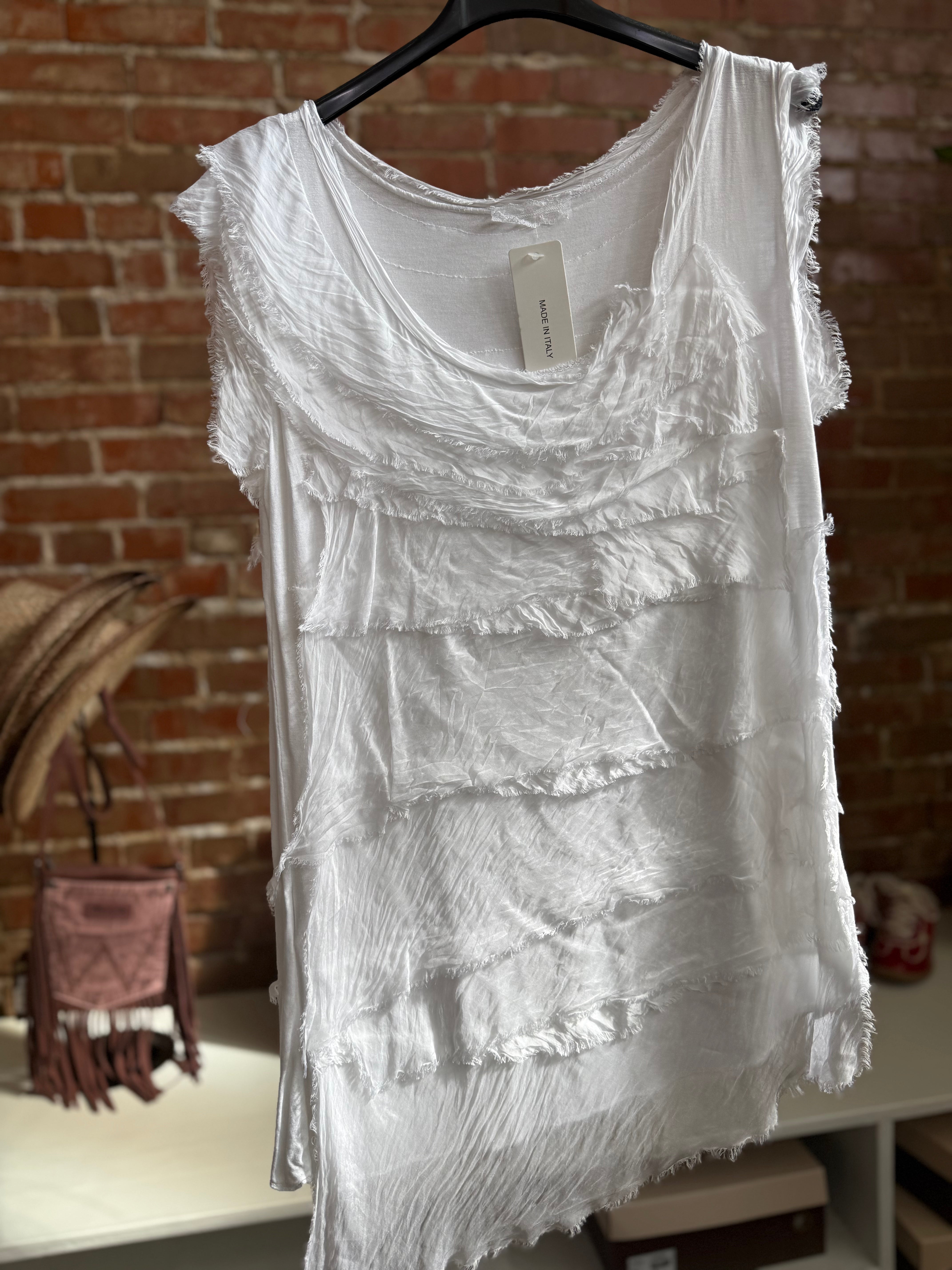 White lace dress on a hanger against a brick wall.