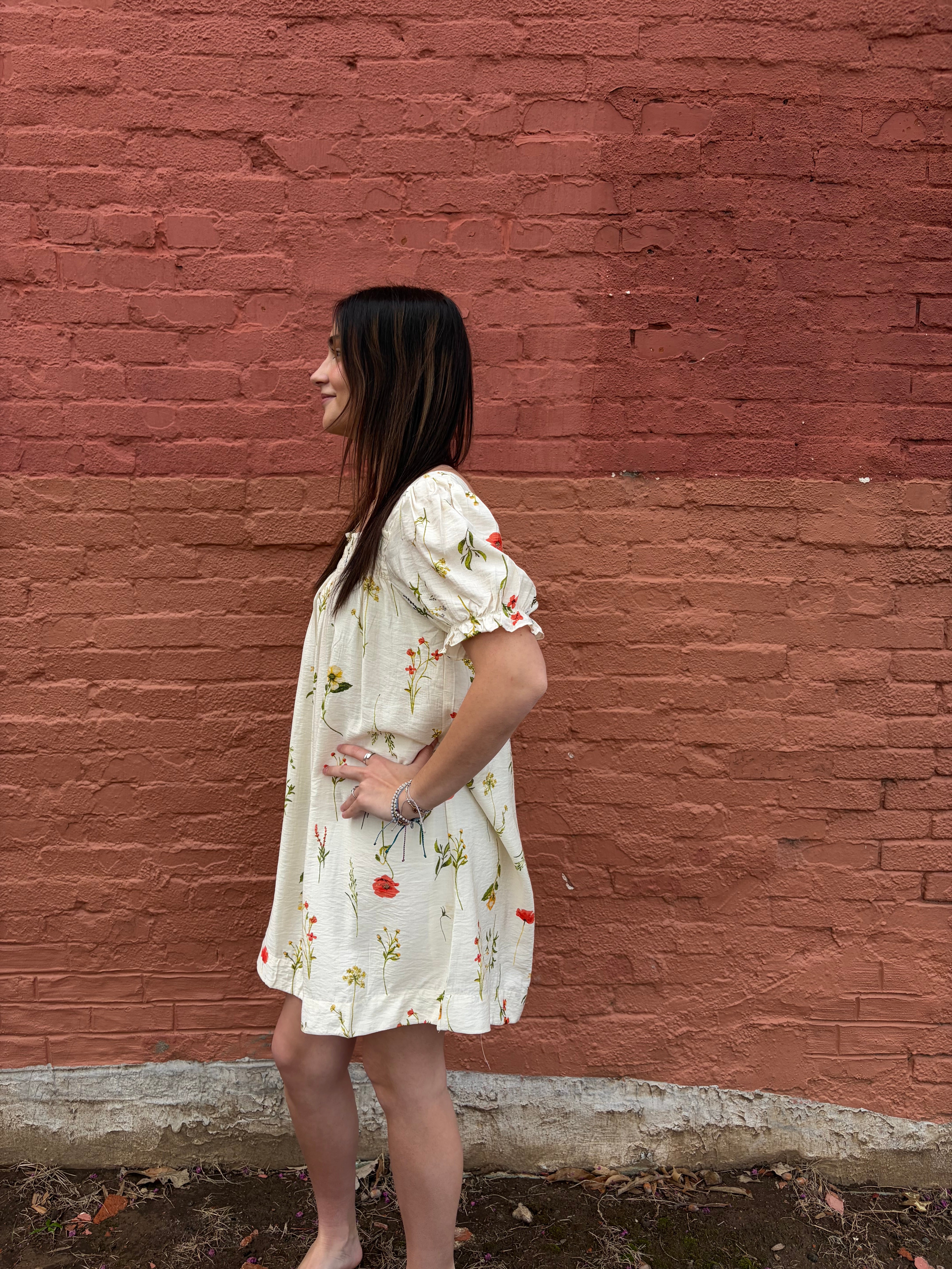 Person wearing a floral dress standing on a red brick surface