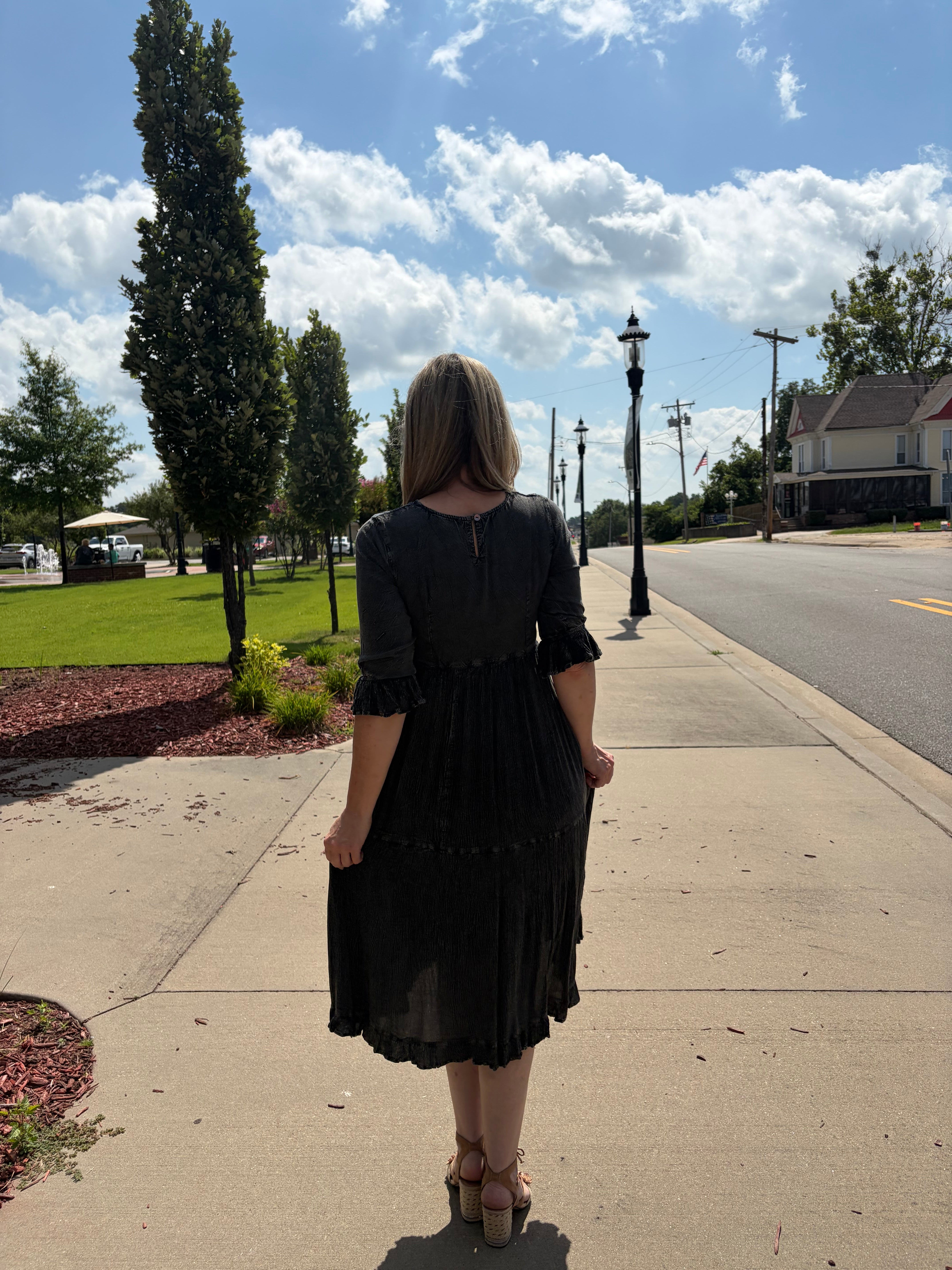 Back view of charcoal denim fusion tiered midi dress with 3/4 ruffle sleeves and tiered skirt