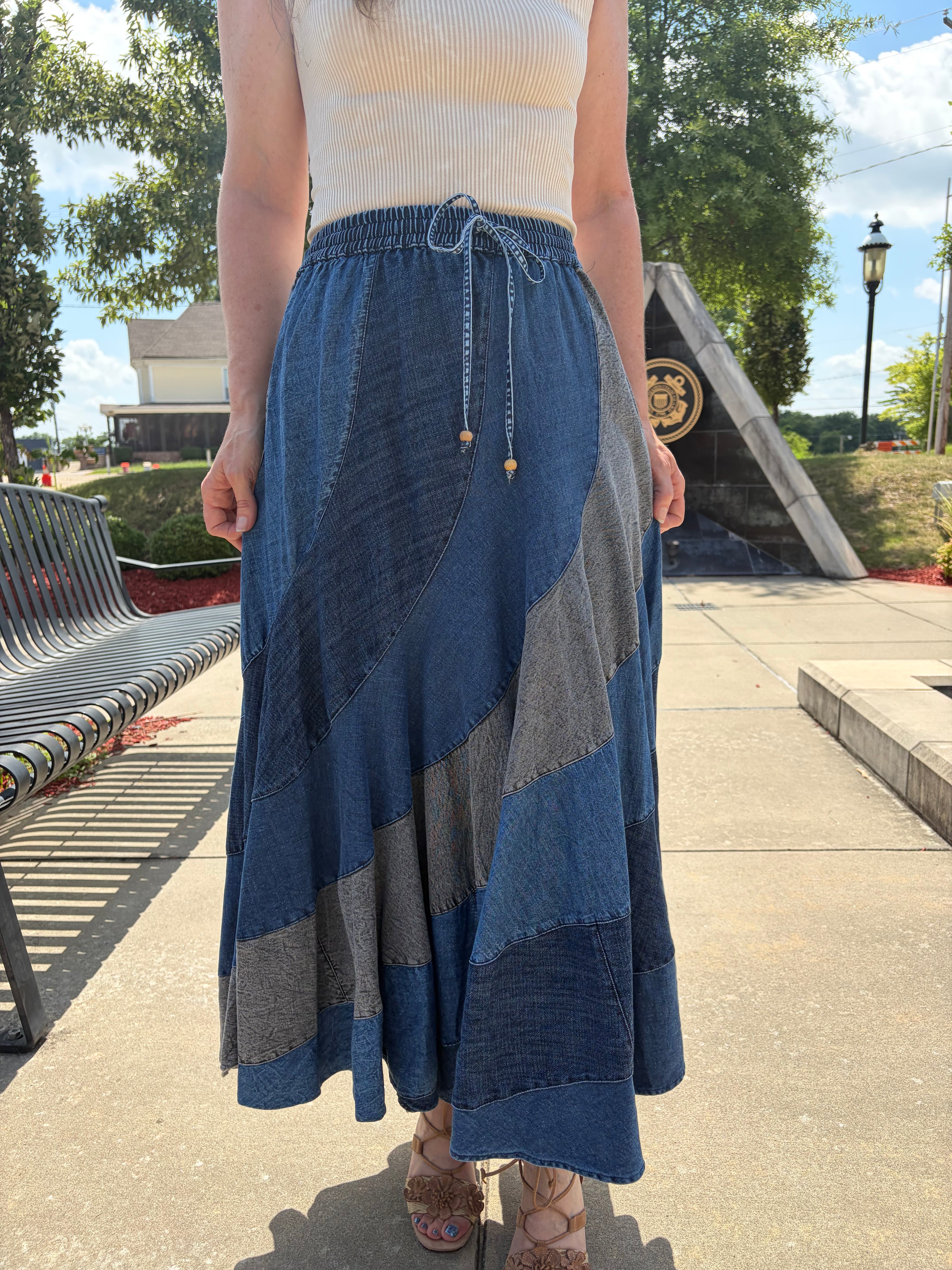 Front close-up of the drawstring waistband and asymmetrical color-washed denim patchwork panels