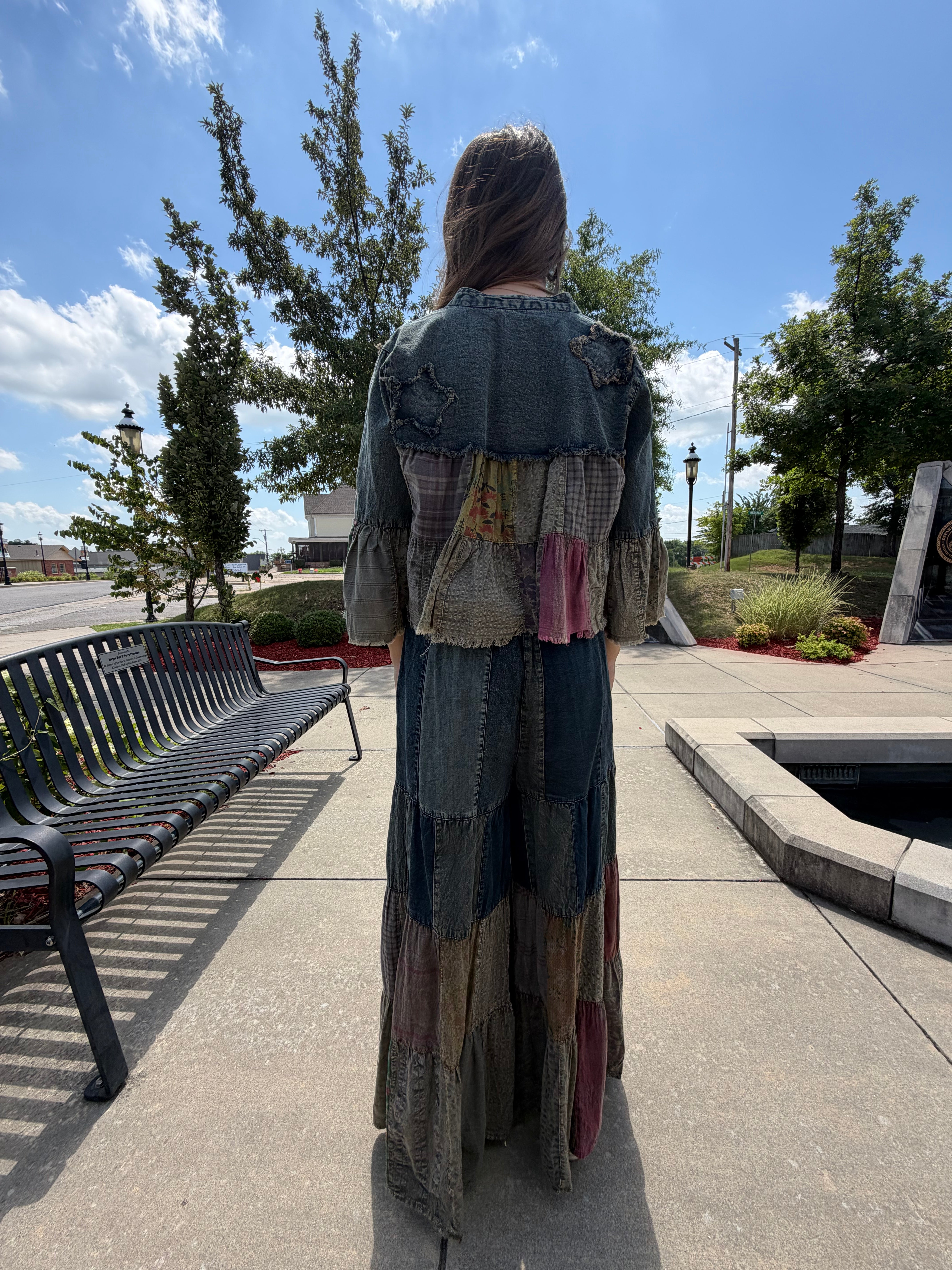 Full back view styled over a patchwork maxi skirt, showing the shrug's cropped length and layered patchwork hem