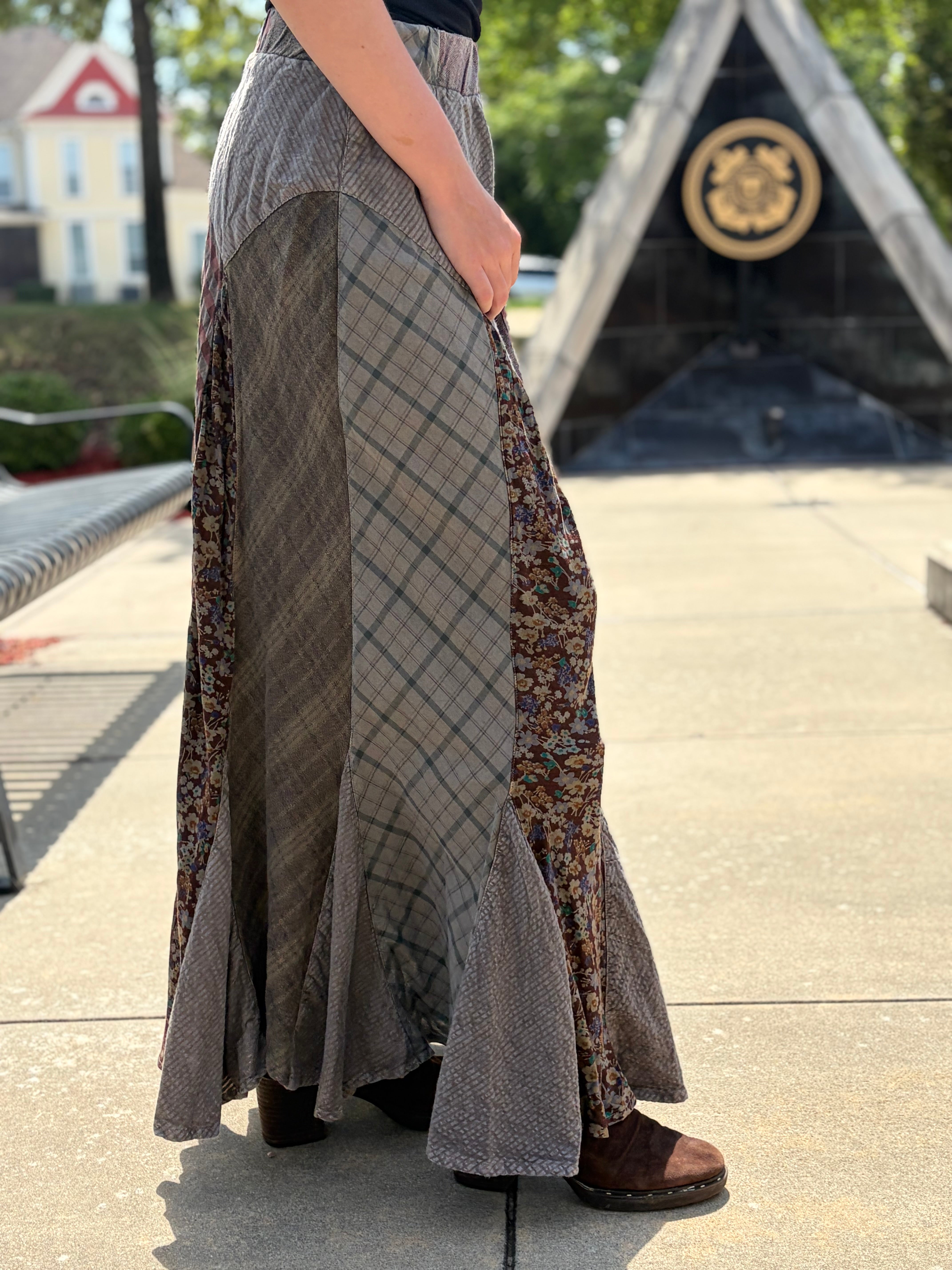 Side view of patchwork maxi skirt showing plaid and floral panel detail with ruffled hem, elasticated waistband, styled with black tank and brown boots