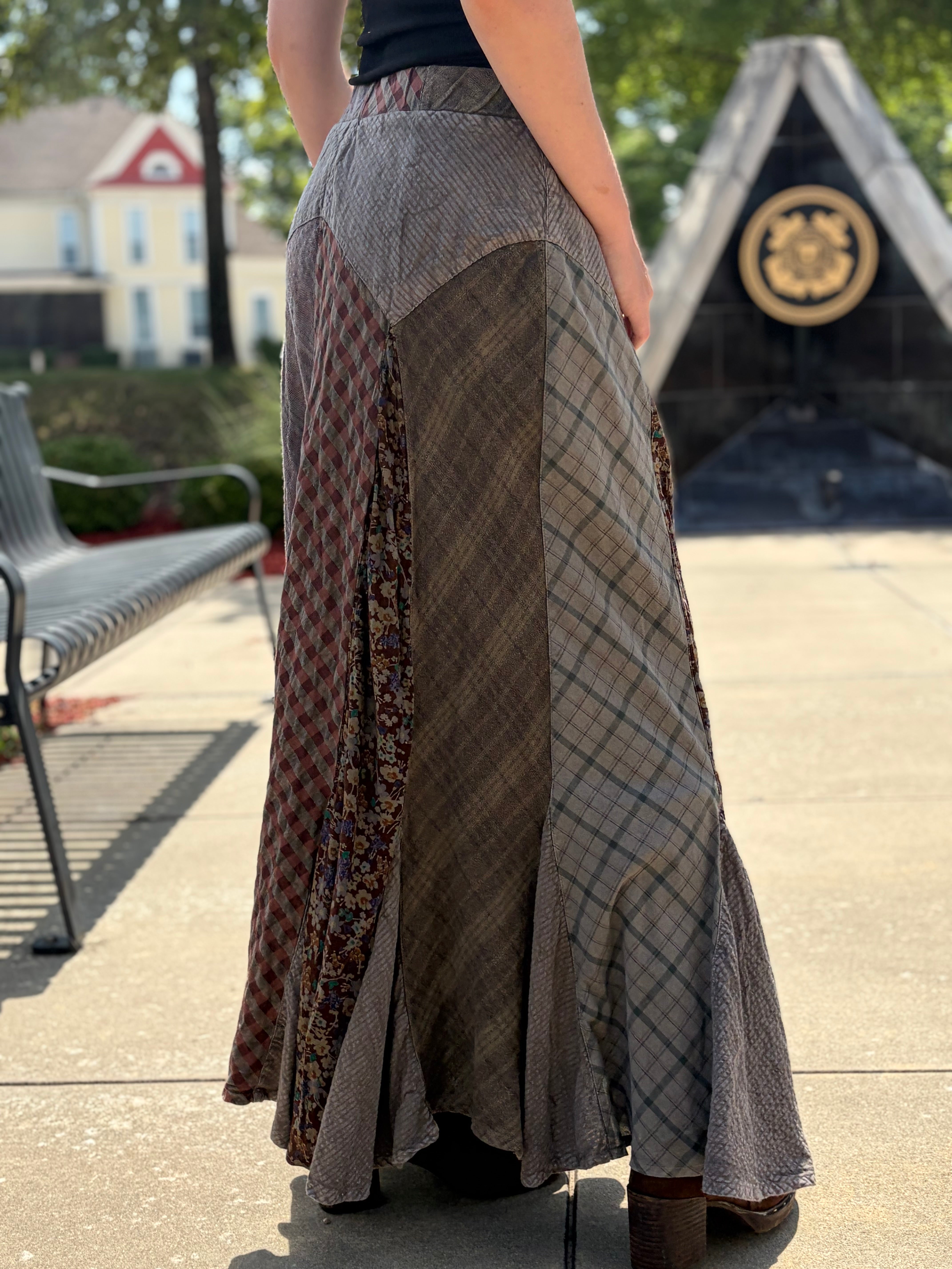 Back view of boho patchwork maxi skirt with diagonal plaid and floral panels, ruffled hem and elasticated waistband, styled with black tank top