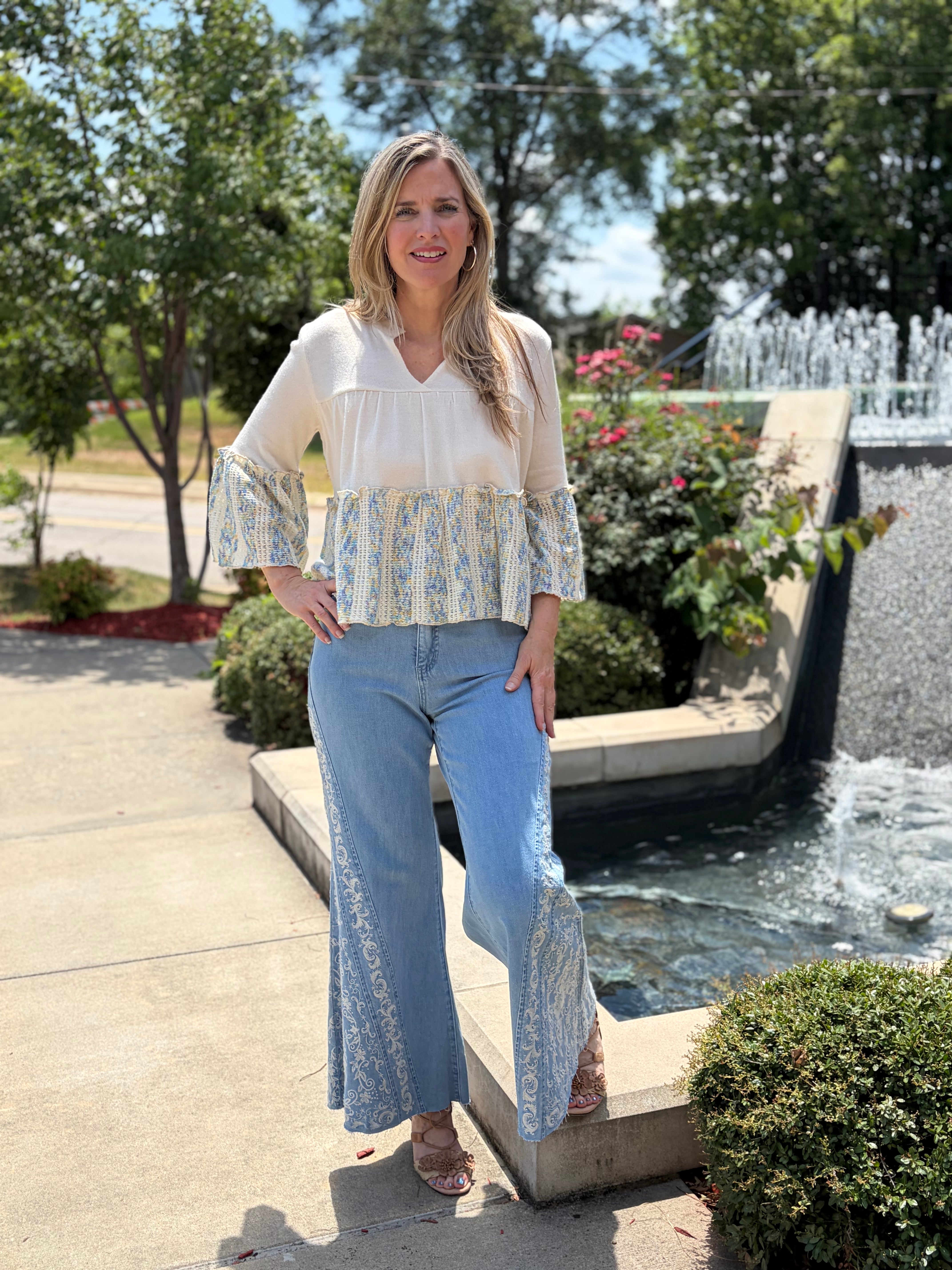 Outdoor full-body front, smiling near fountain, wide-leg embroidered jeans + strappy sandals