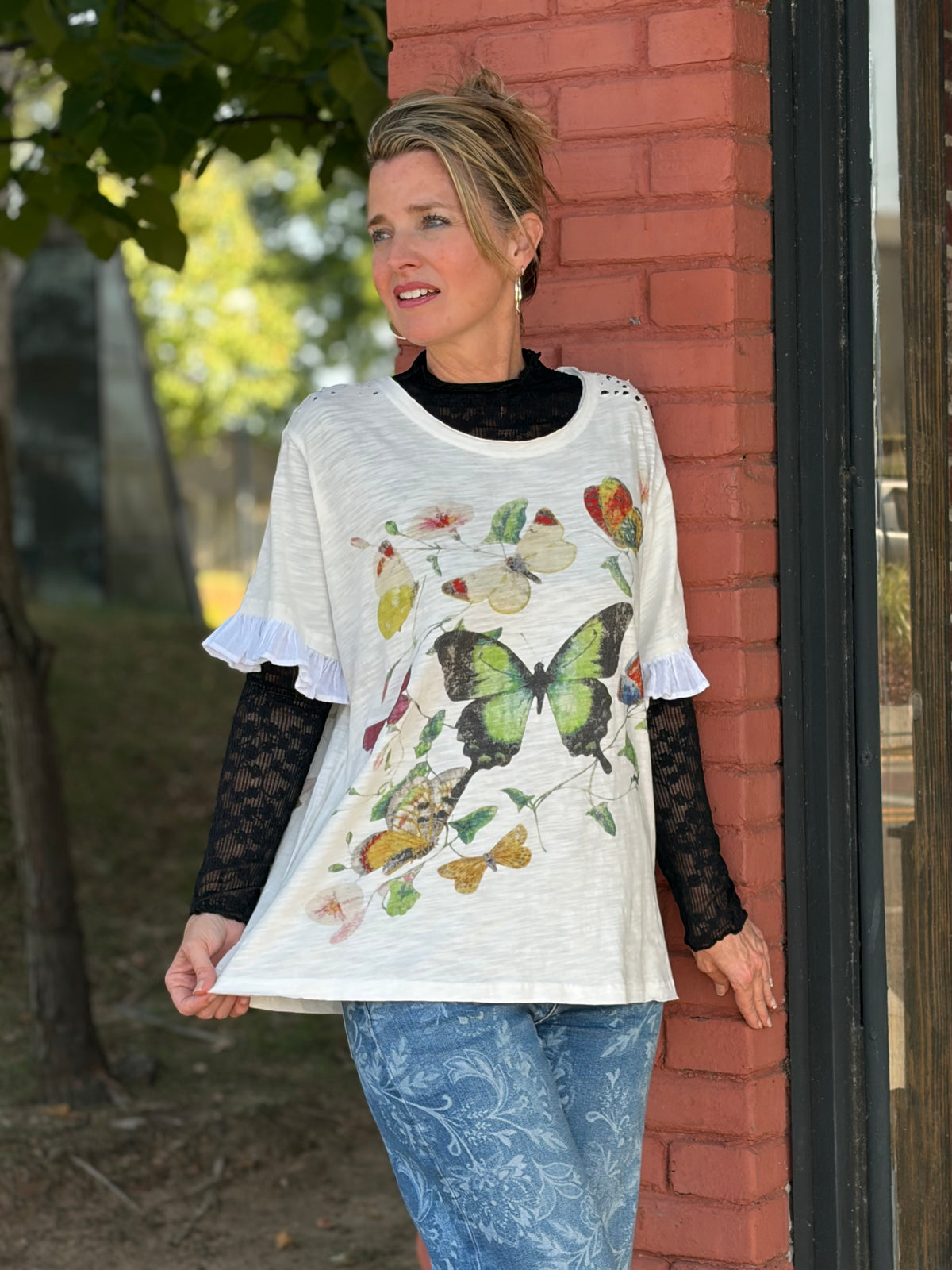 White butterfly and floral botanical print top with ruffle sleeves, layered boho styling with floral jeans — Spirit & Wind Boutique
