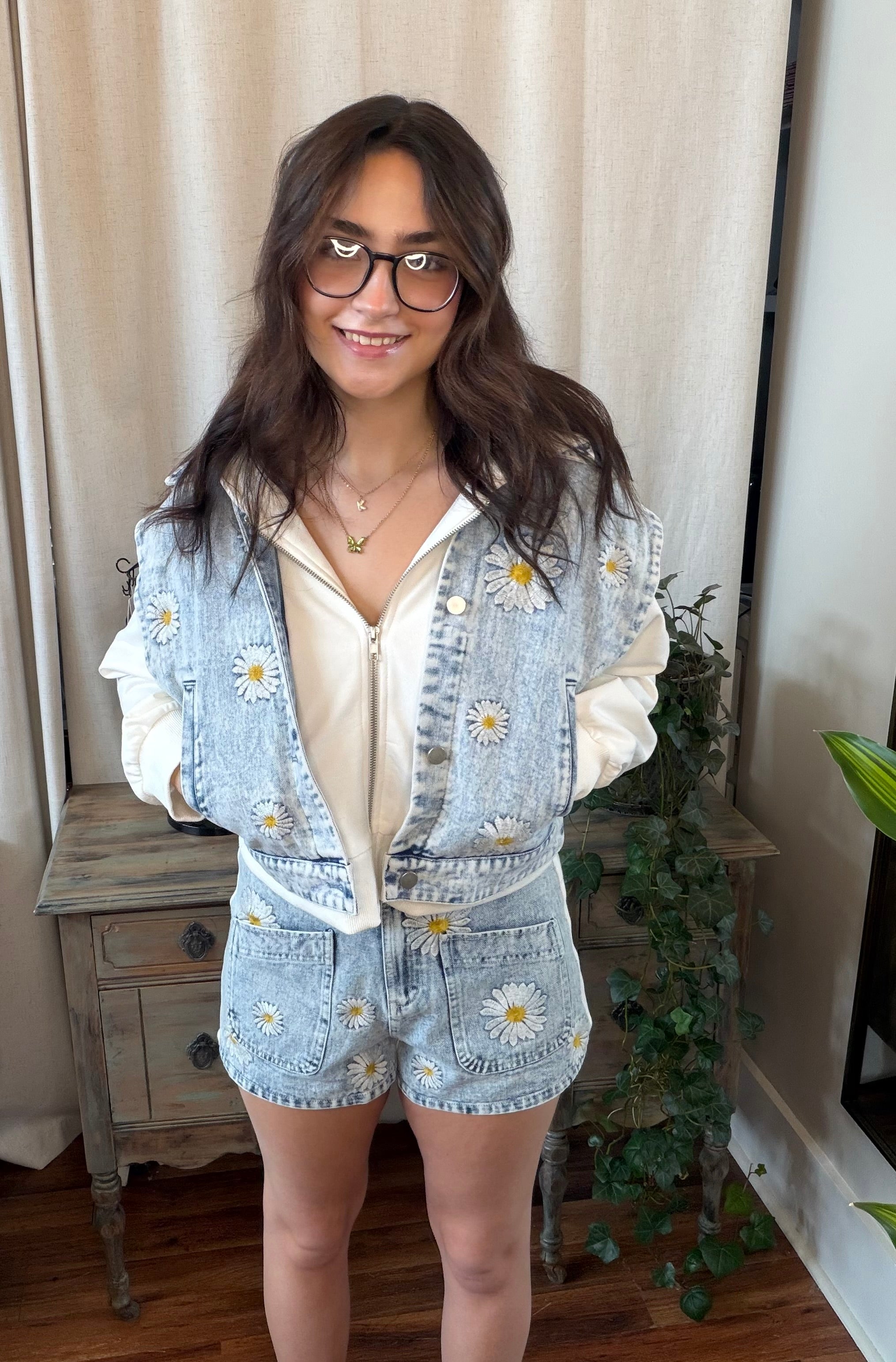 Woman wearing a denim outfit with floral patterns indoors.