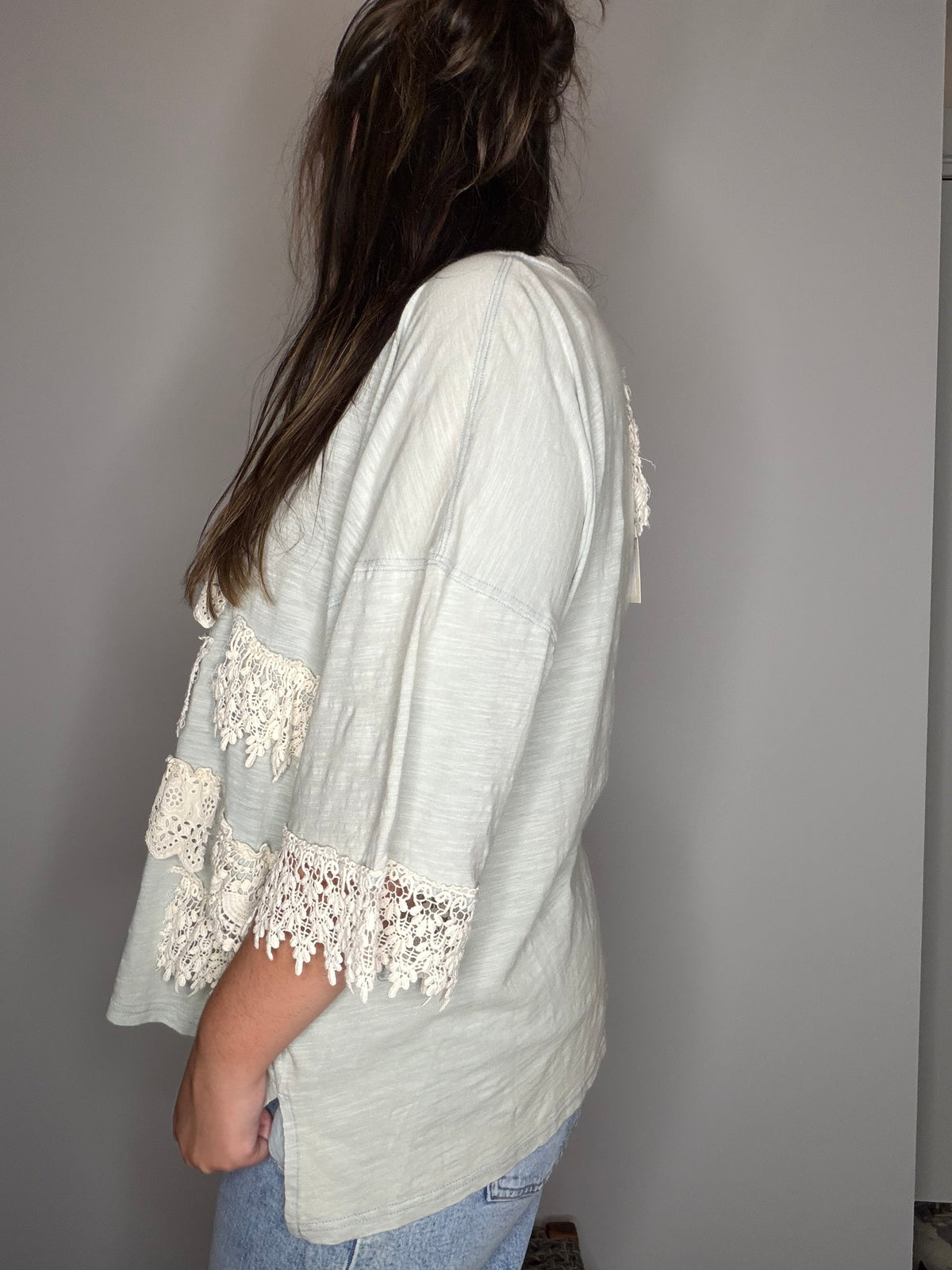 Side profile: cream-white colorway showing relaxed silhouette and lace sleeve trim