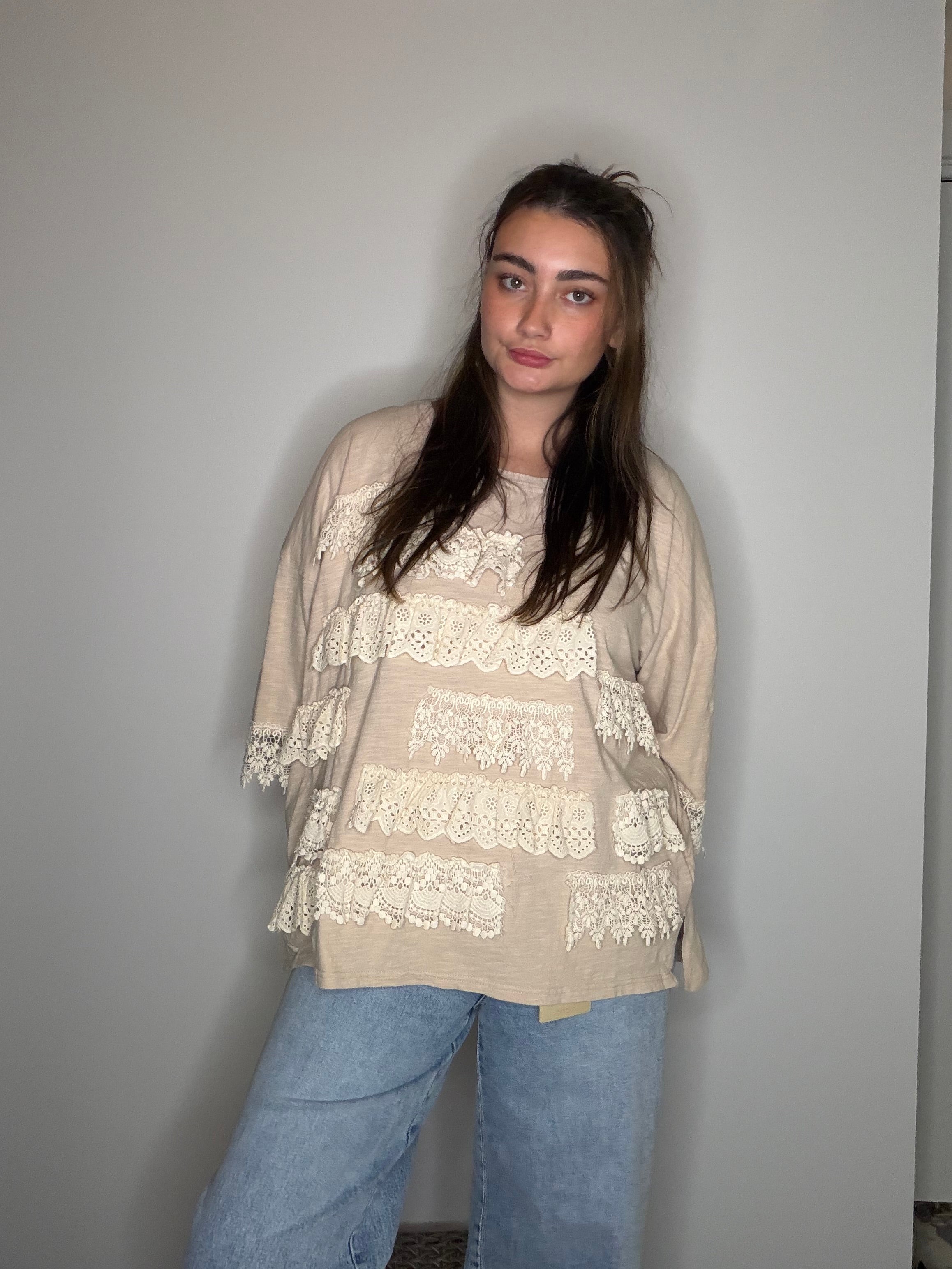 Front facing: tiered cream crochet lace ruffle panels, three-quarter sleeves, jeans