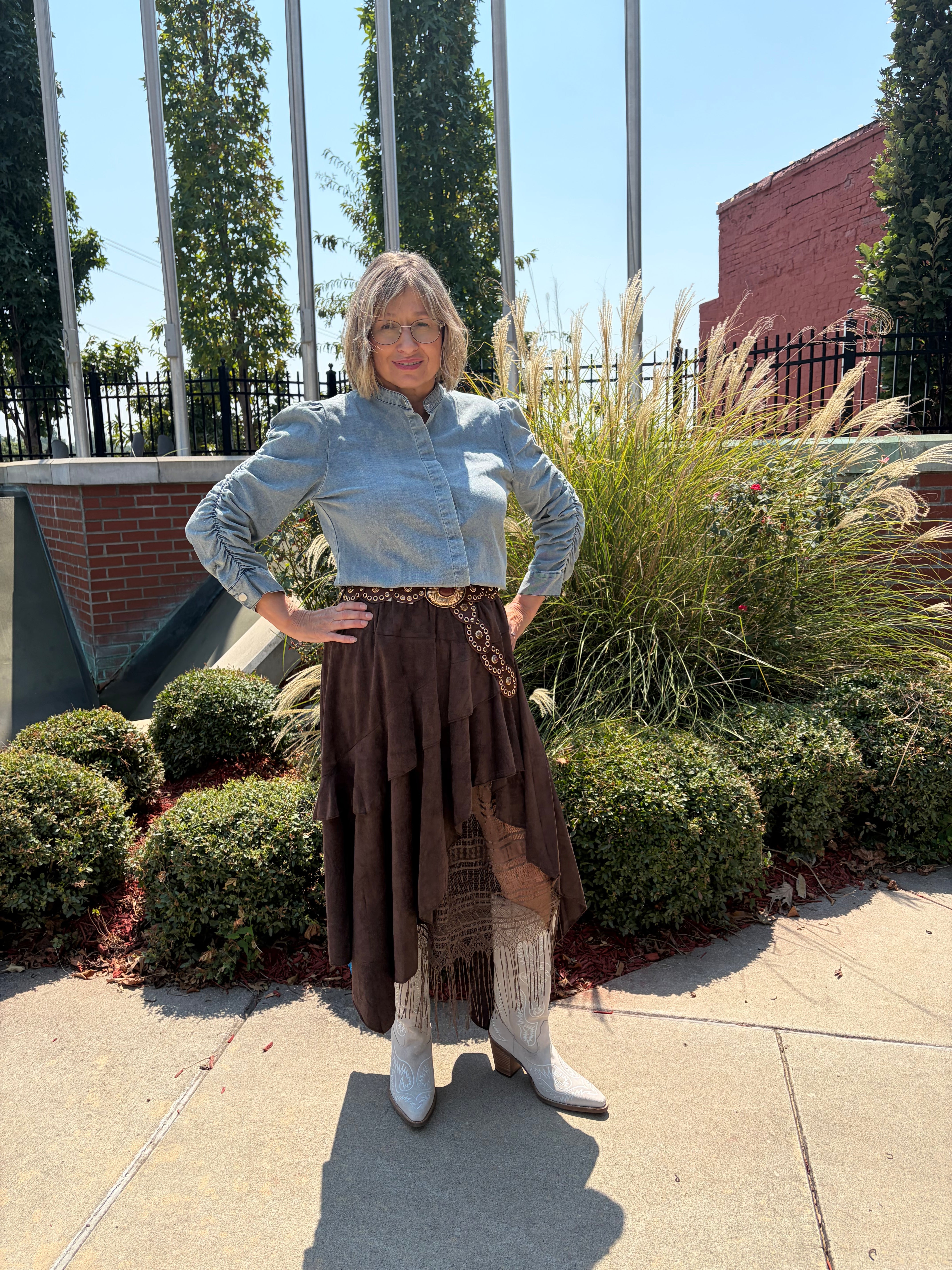 oho Layered Lace Skirt in dark chocolate brown with asymmetrical layered hem and lace fringe, full-length front view outdoors styled with light blue denim top and white cowboy boots