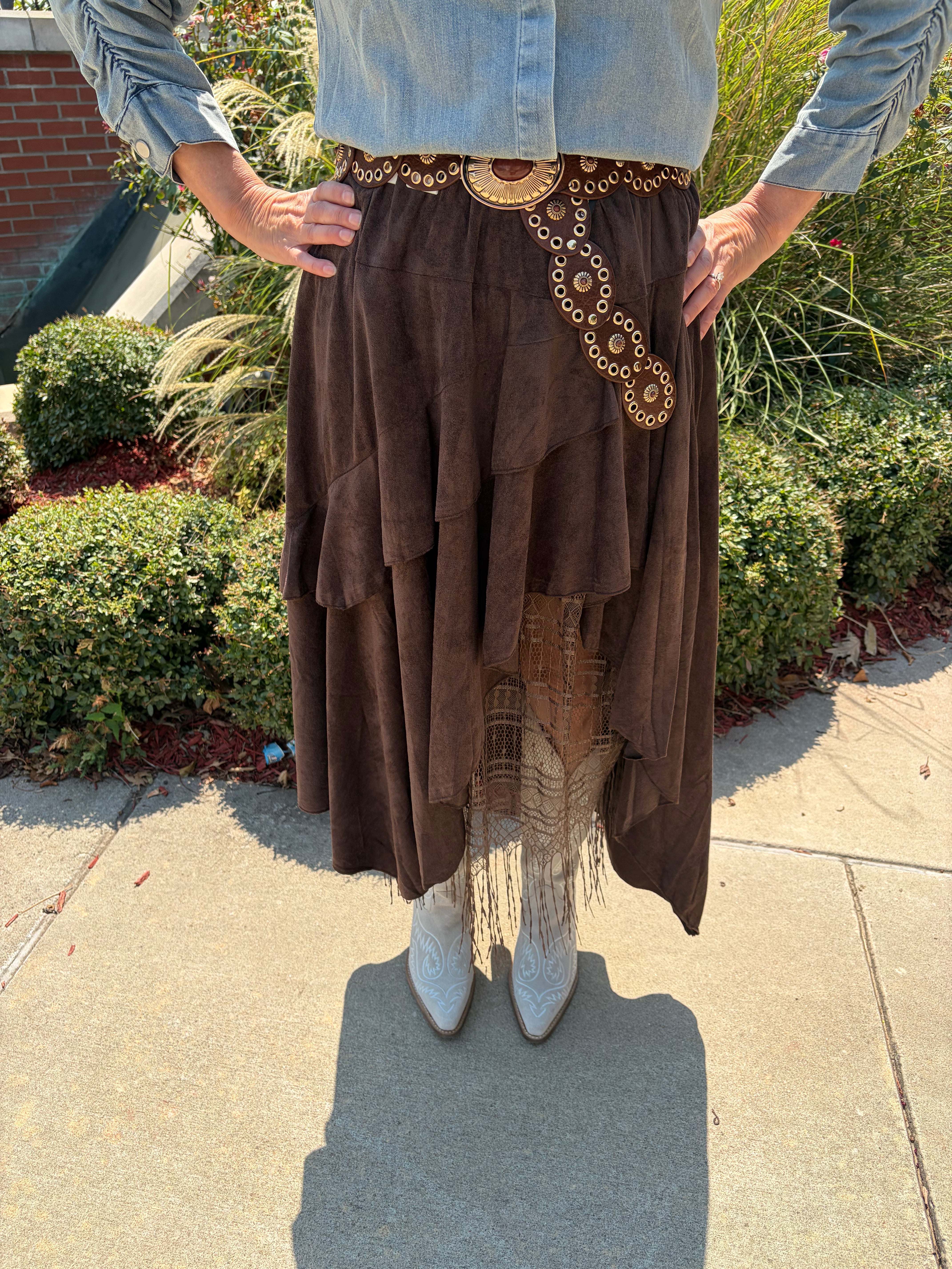 Close-up of Boho Layered Lace Skirt showing dark brown suede-like layered tiers, lace and fringe hem detail, and boho grommet belt at waist