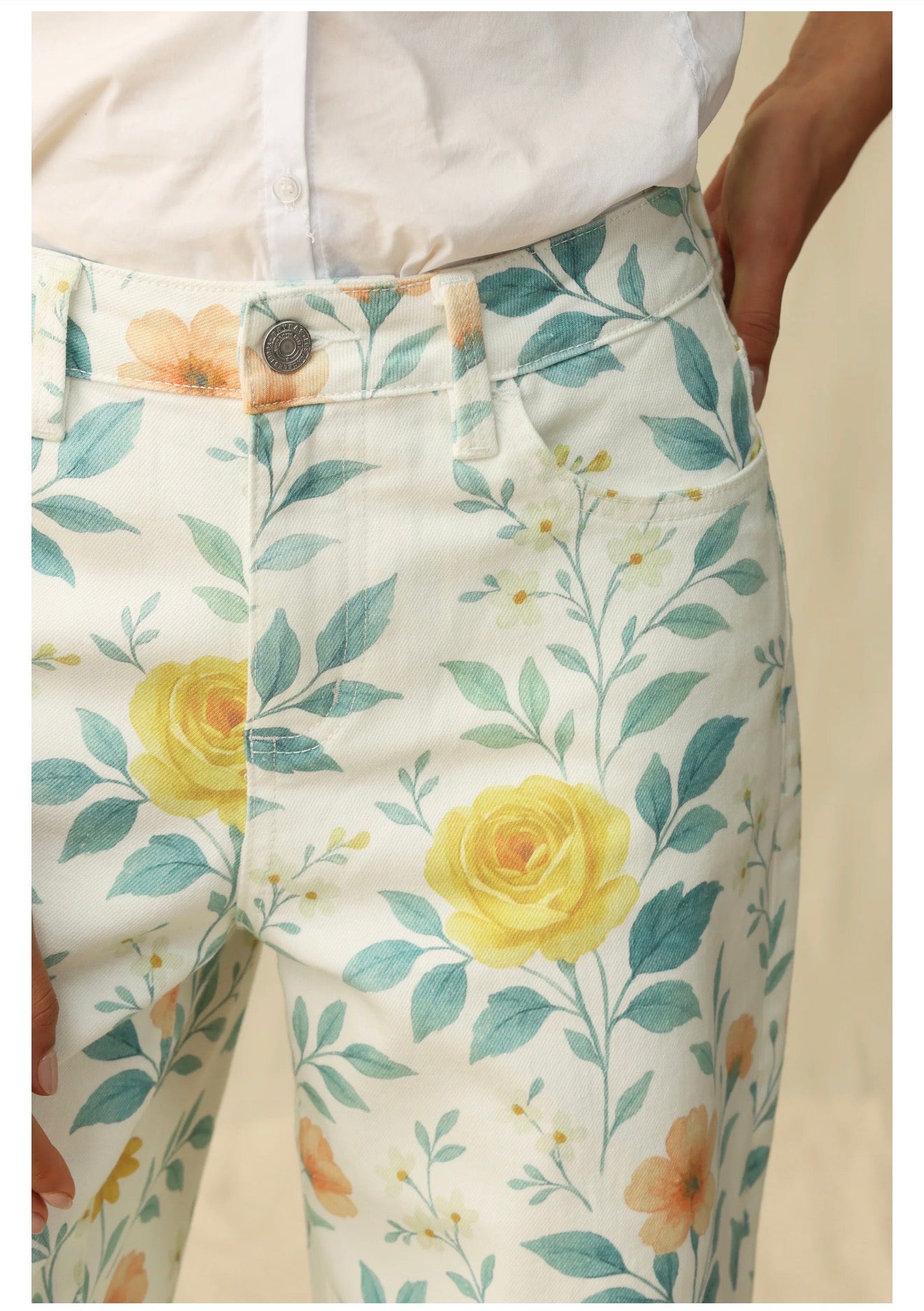 Floral-patterned pants with yellow roses and green leaves on a white background