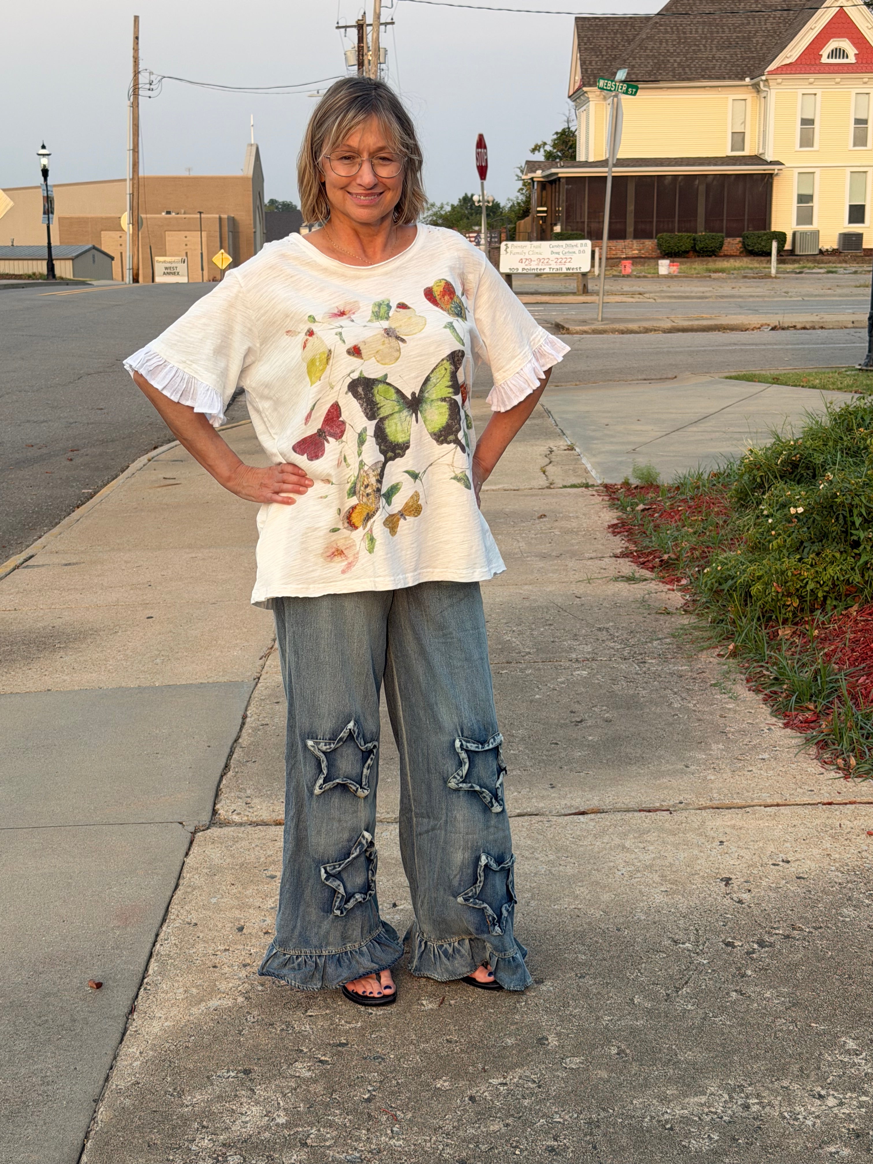 Front view of woman wearing Blue Velvet ruffled star patch denim pants showing double star appliques and ruffled hem
