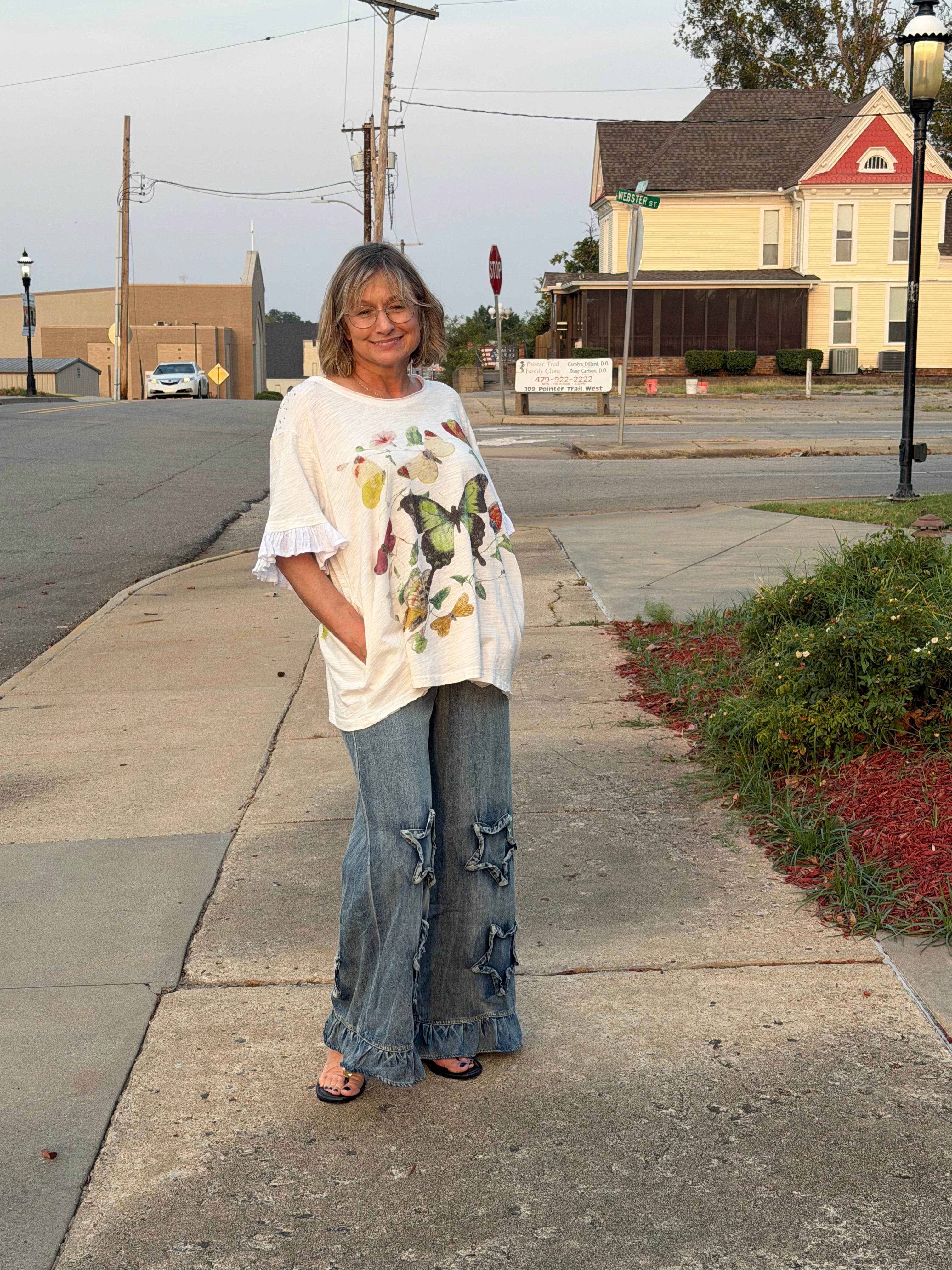 Front view of woman wearing Blue Velvet ruffled star patch denim pants showing double star appliques and ruffled hem