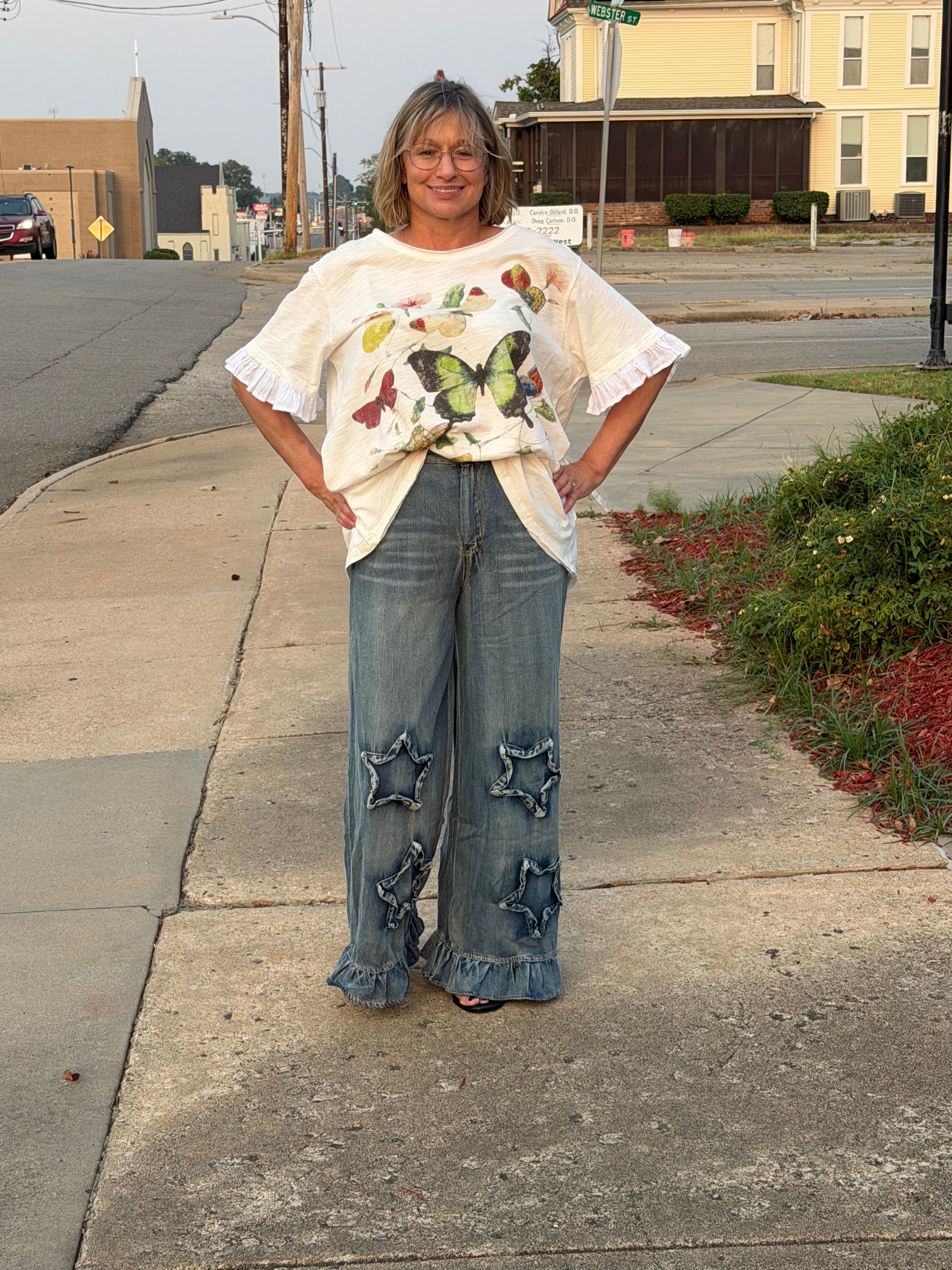 Front view of woman wearing Blue Velvet ruffled star patch denim pants showing double star appliques and ruffled hem
