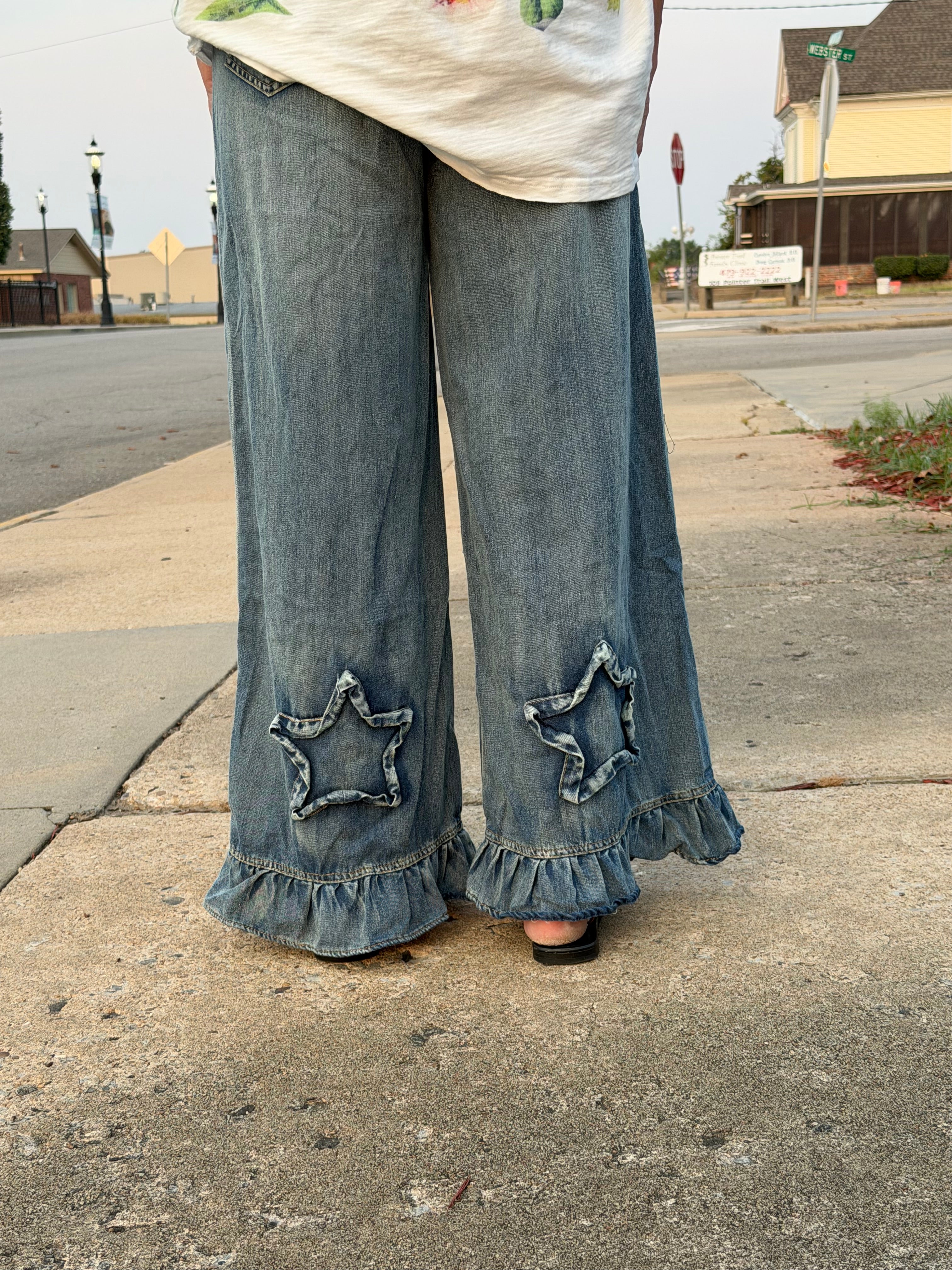 Close-up back view of Blue Velvet ruffled star patch wide leg denim pants showing denim star appliques and ruffled hem detail