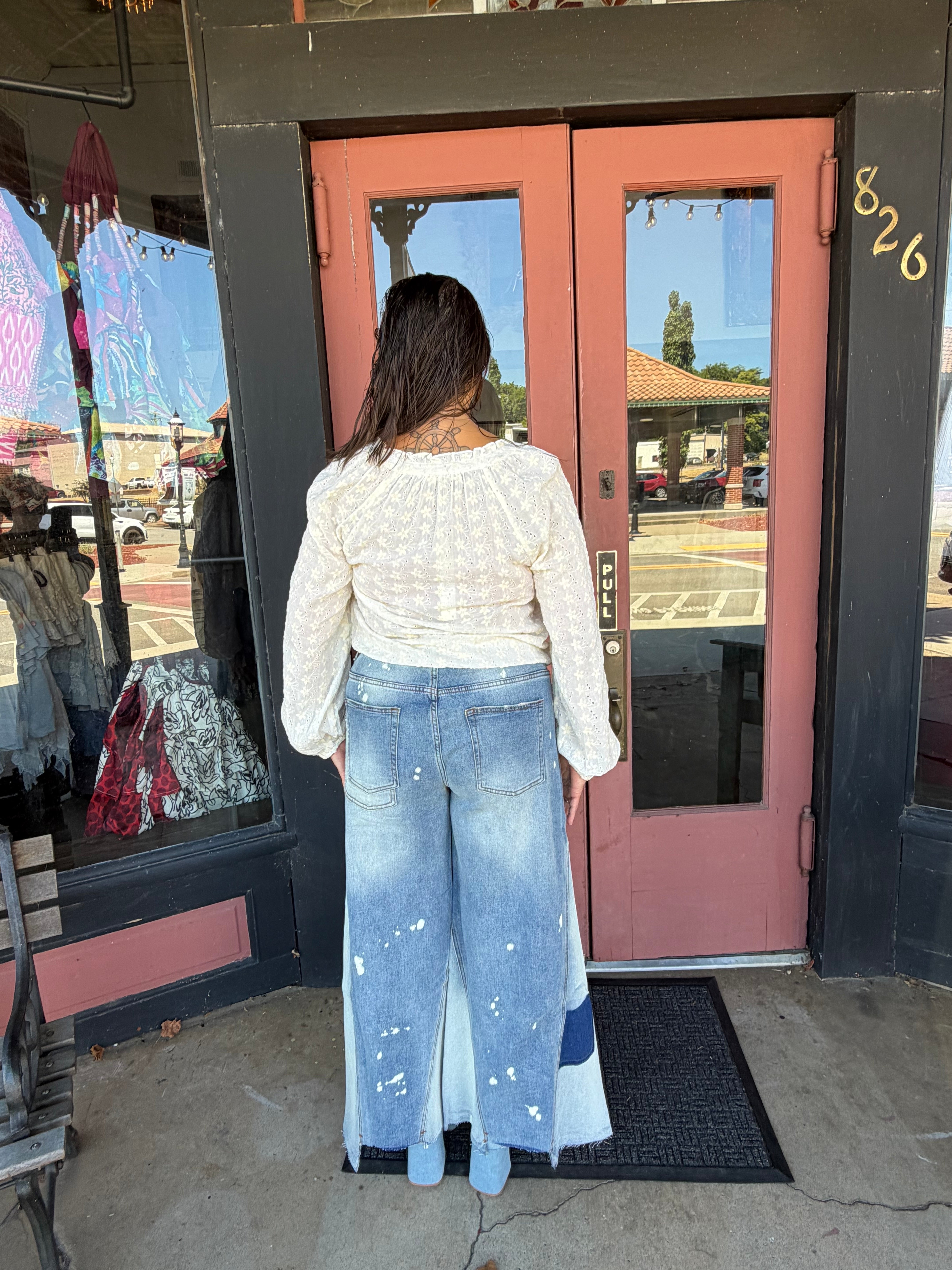Woman in a white floral eyelet blouse, three-quarter front view showing ruffle V-neckline and long sleeve silhouette back view