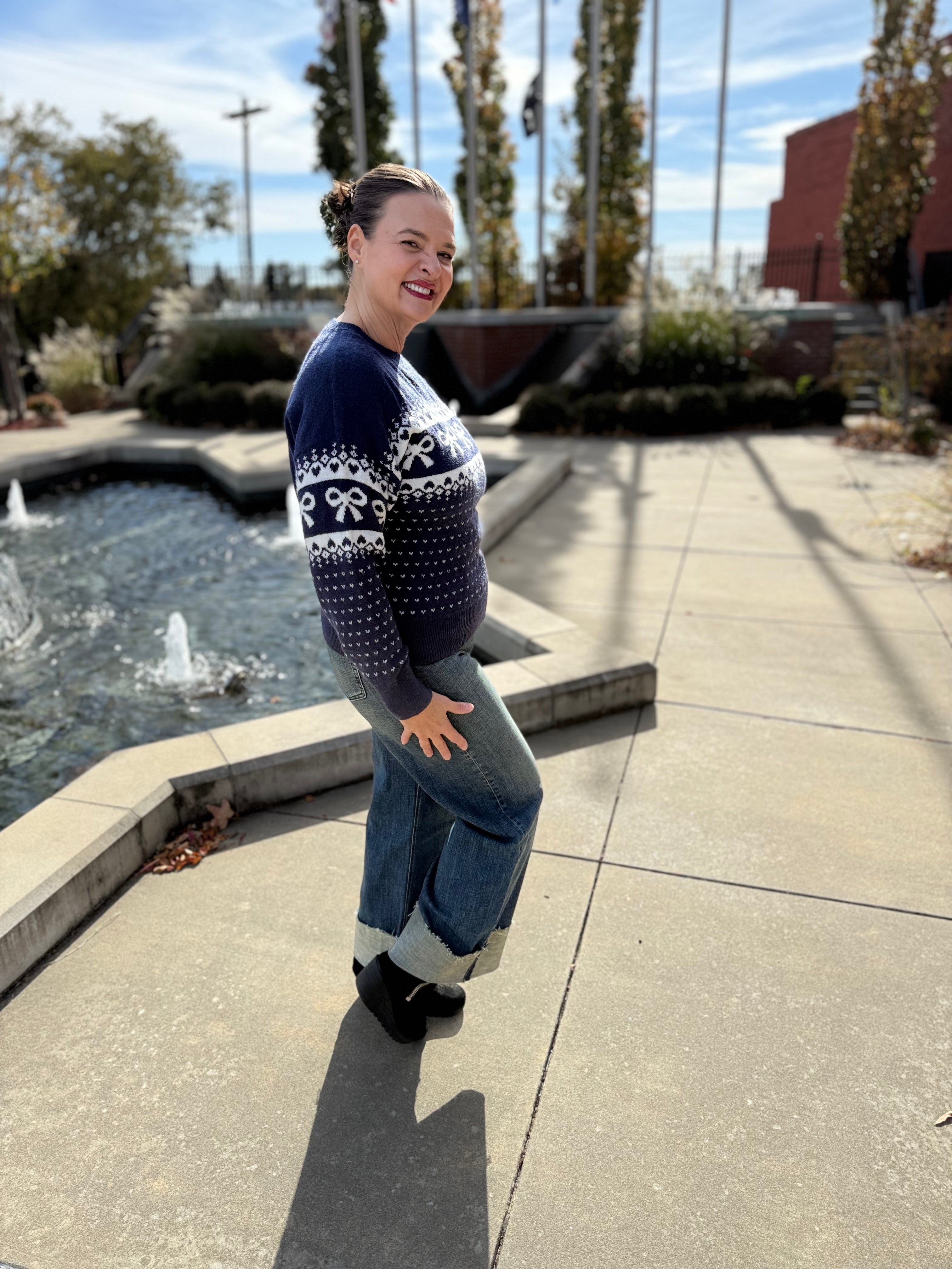 Woman in a patterned sweater and jeans standing by a fountain