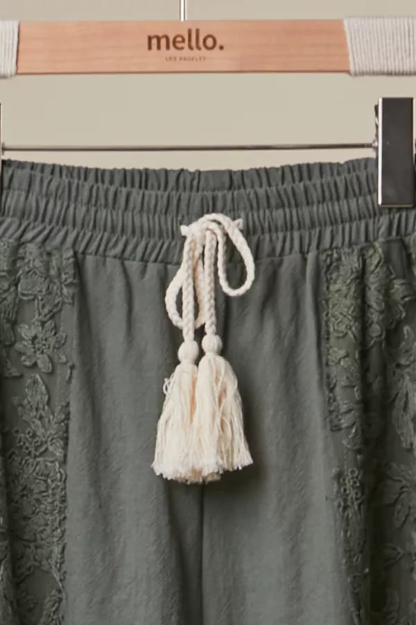 Green skirt with tassel detail on a hanger with 'mello' brand visible