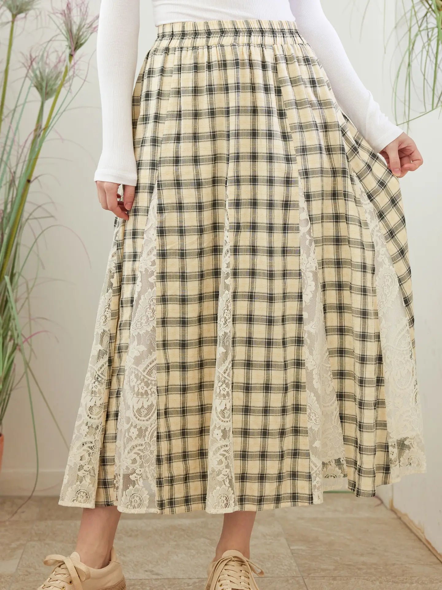 Person wearing a plaid skirt with lace trim in an indoor setting