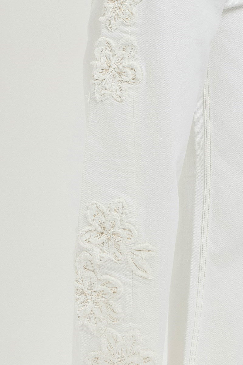 Close-up of a white garment with floral embroidery on a light background