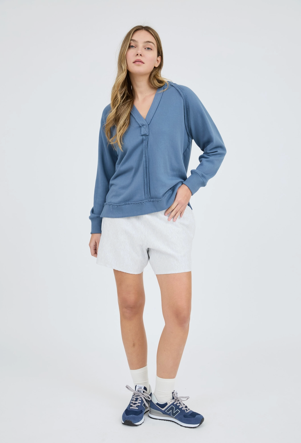Woman wearing a blue sweater and white shorts on a white background