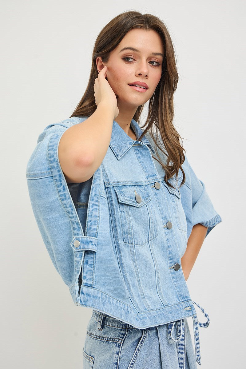 Woman wearing a light blue denim jacket on a plain background