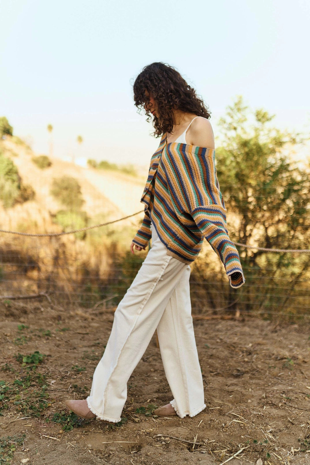 Woman walking outdoors wearing a slouchy multicolor striped cardigan with light wide-leg jeans for an effortless fall style.