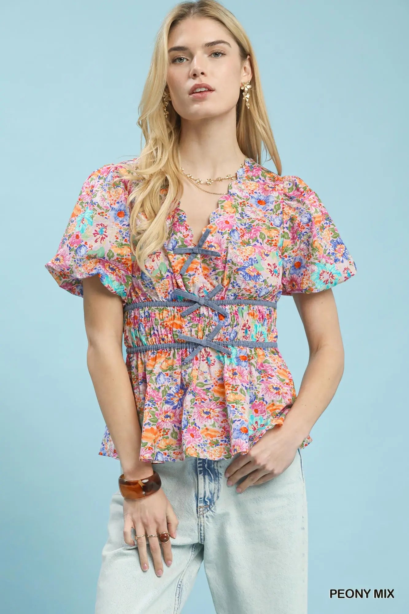 Woman wearing a colorful floral blouse against a light blue background