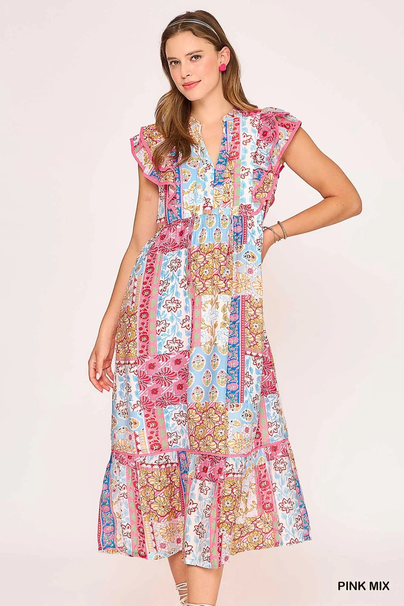 Woman wearing a colorful patchwork dress on a light pink background