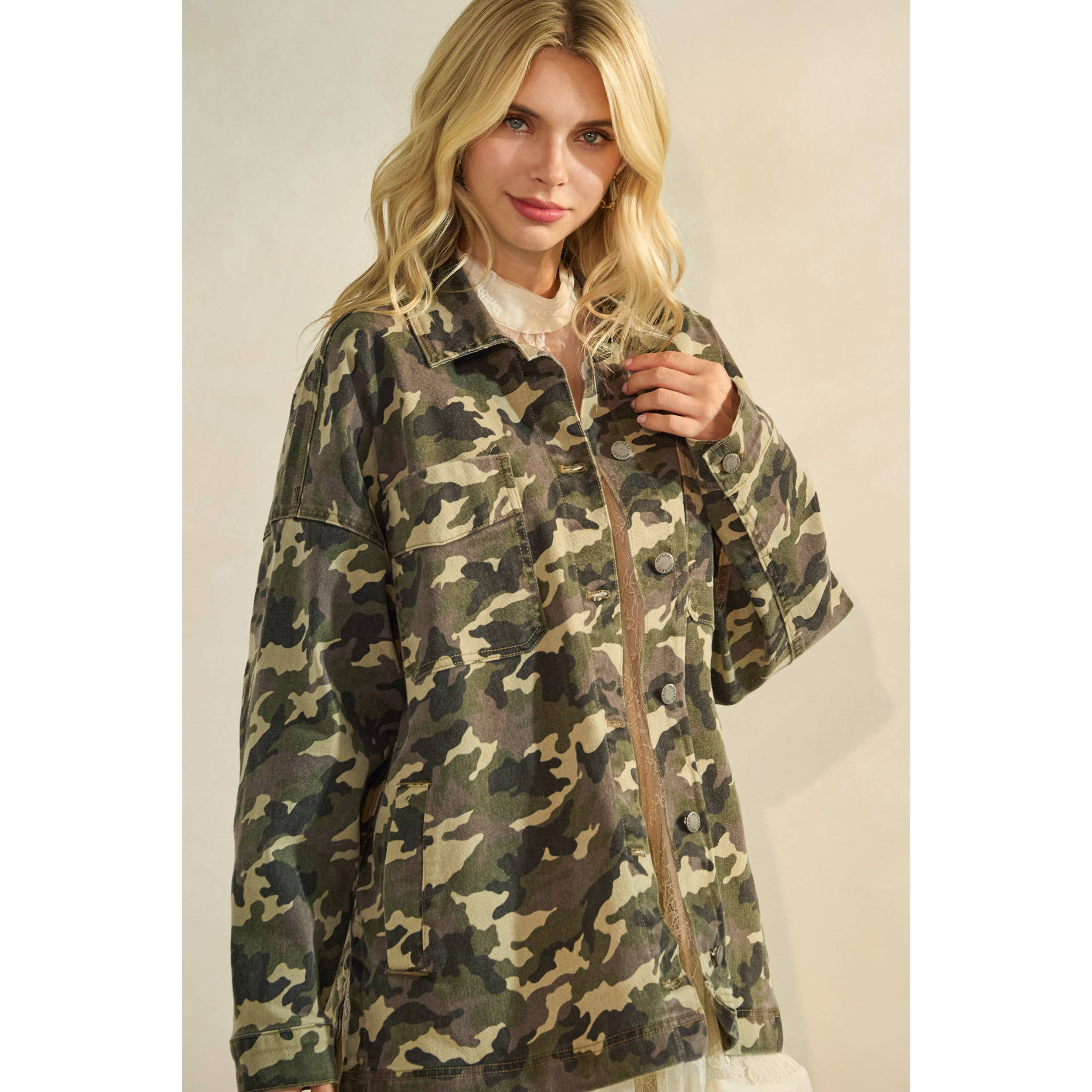 Oversized camouflage print jacket with front pockets and button closure, styled over a white tiered mini dress.