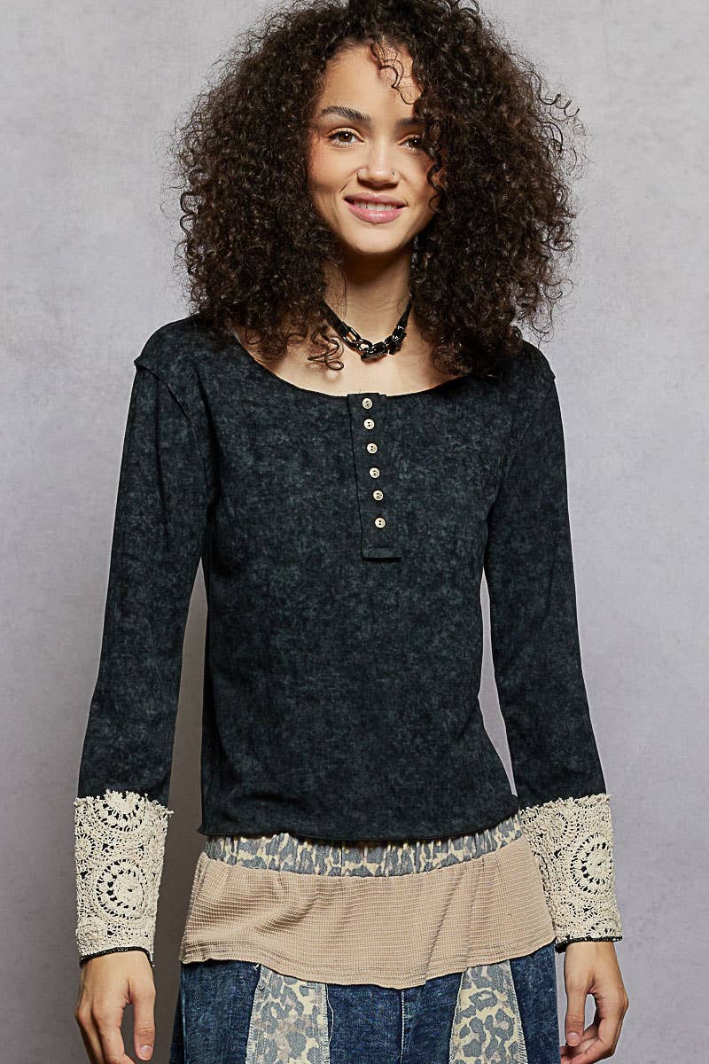 Woman wearing a black long-sleeve top with lace details on a gray background