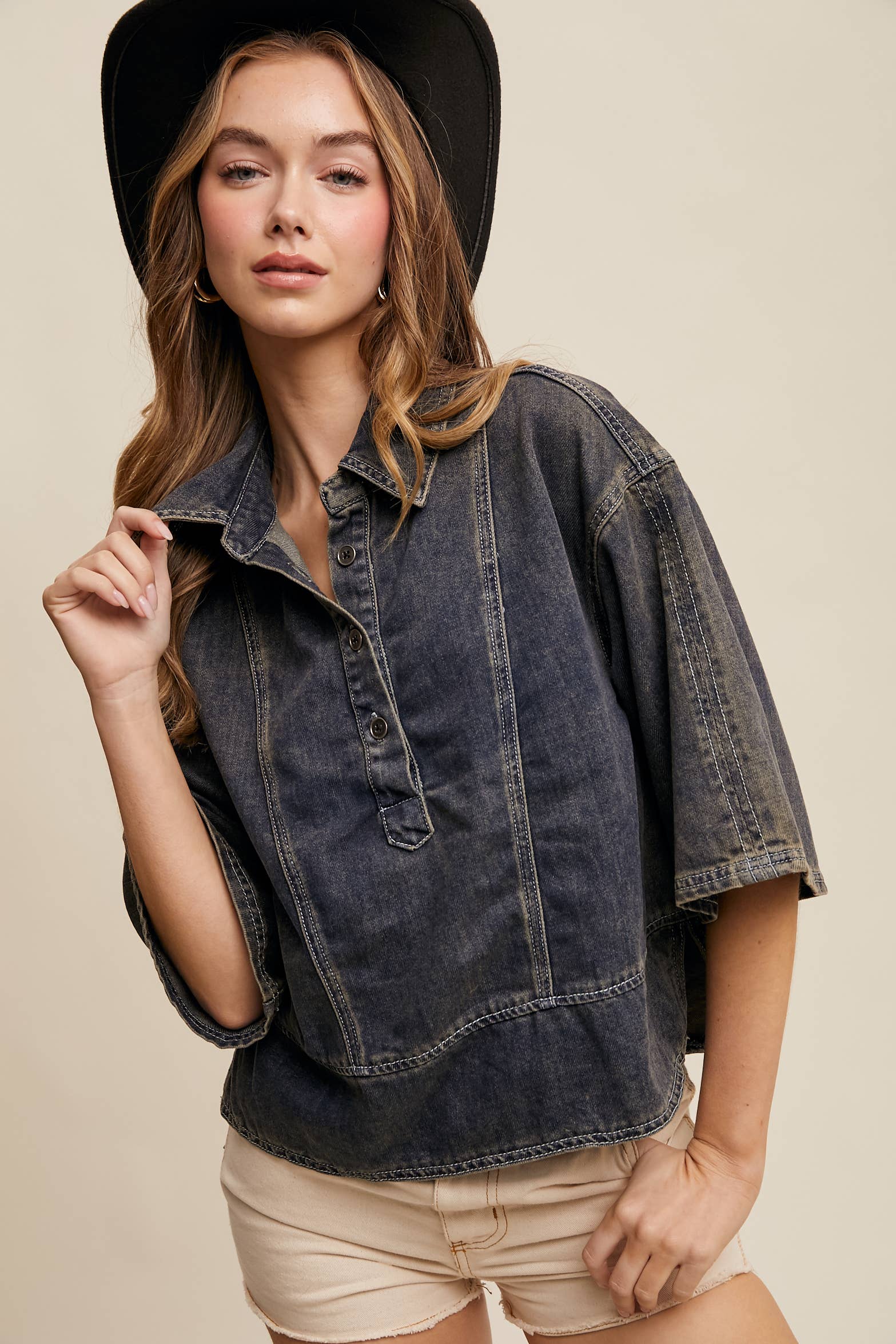 Dark-wash denim pullover top with half-button placket, exposed seam panels, and wide elbow-length sleeves in a relaxed, boxy fit.