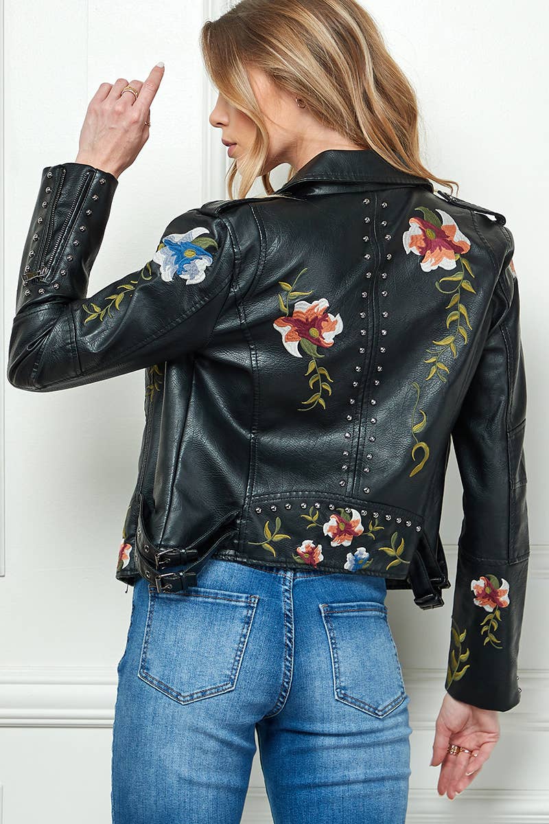 Back view of black faux-leather moto jacket with floral embroidery and silver stud trim, styled with blue jeans.