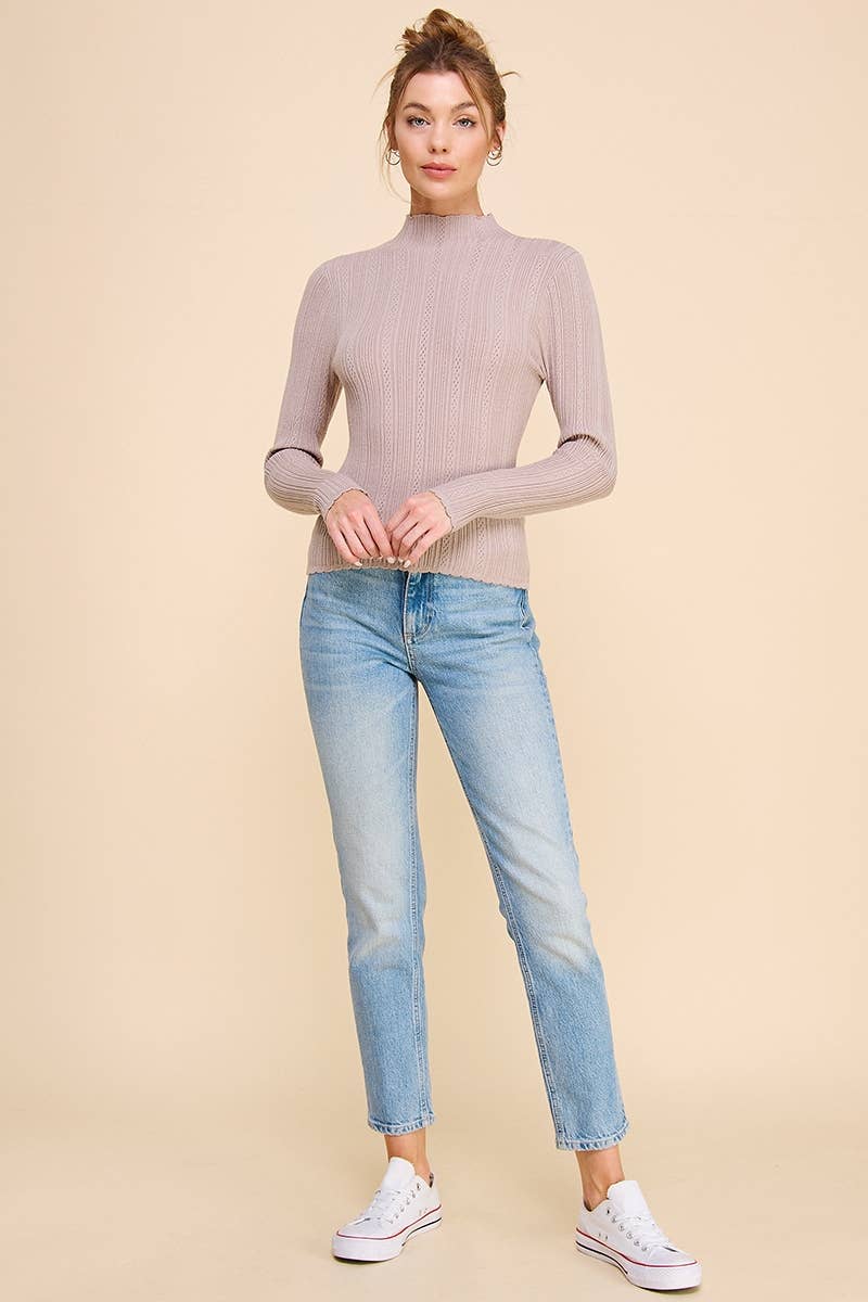 Woman wearing a beige turtleneck sweater and light blue jeans on a beige background