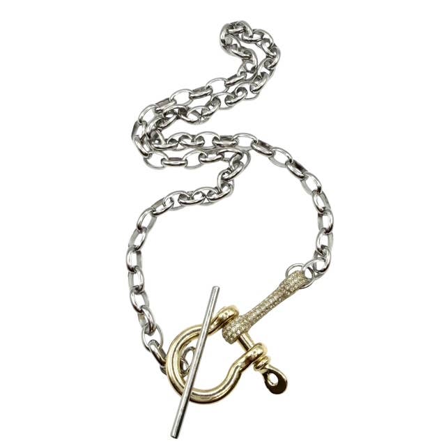 A silver chain necklace with a gold toggle clasp and a textured gold ring detail, displayed on a clean white background.