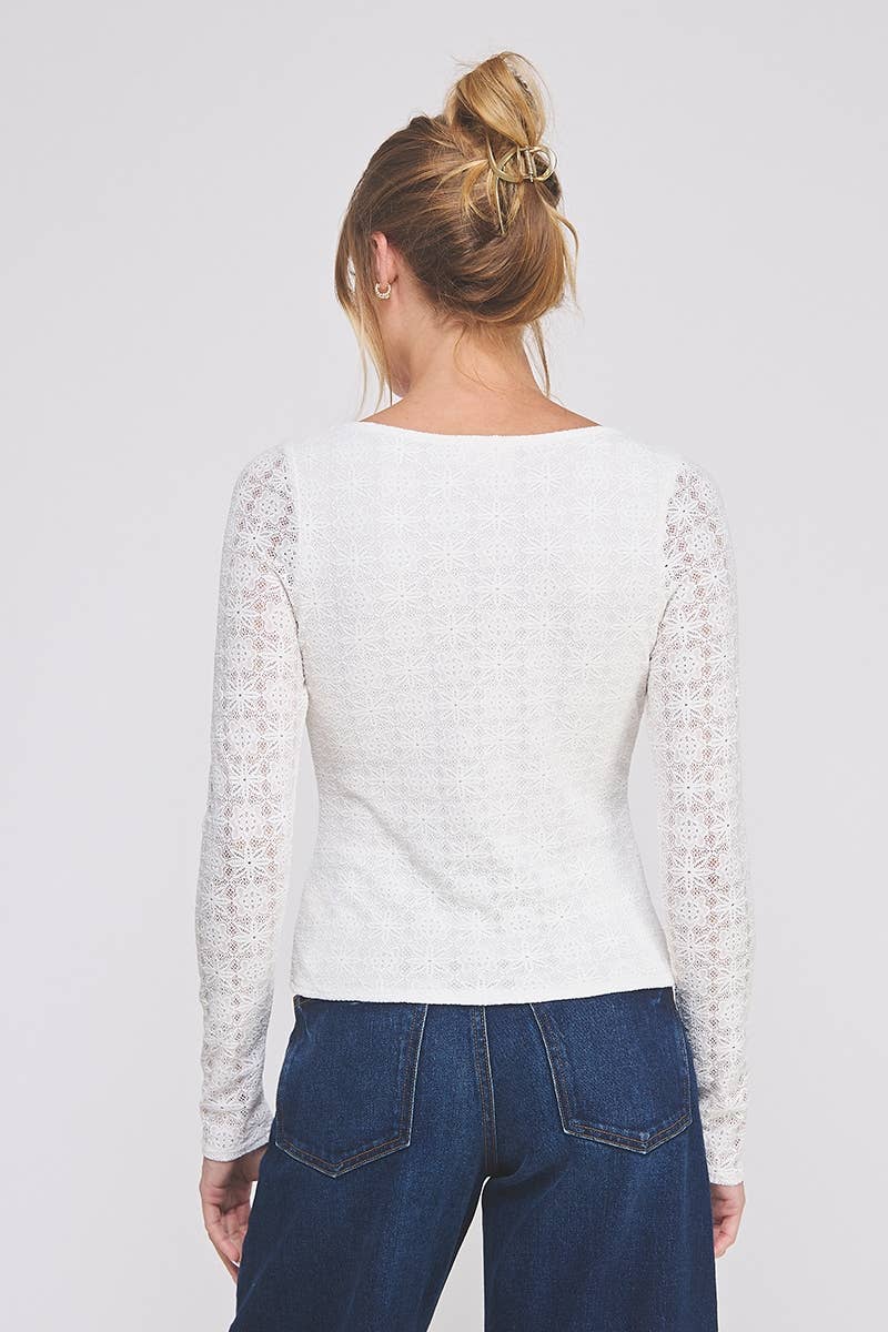 Person wearing a white long-sleeve lace top with lace sleeves on a plain background