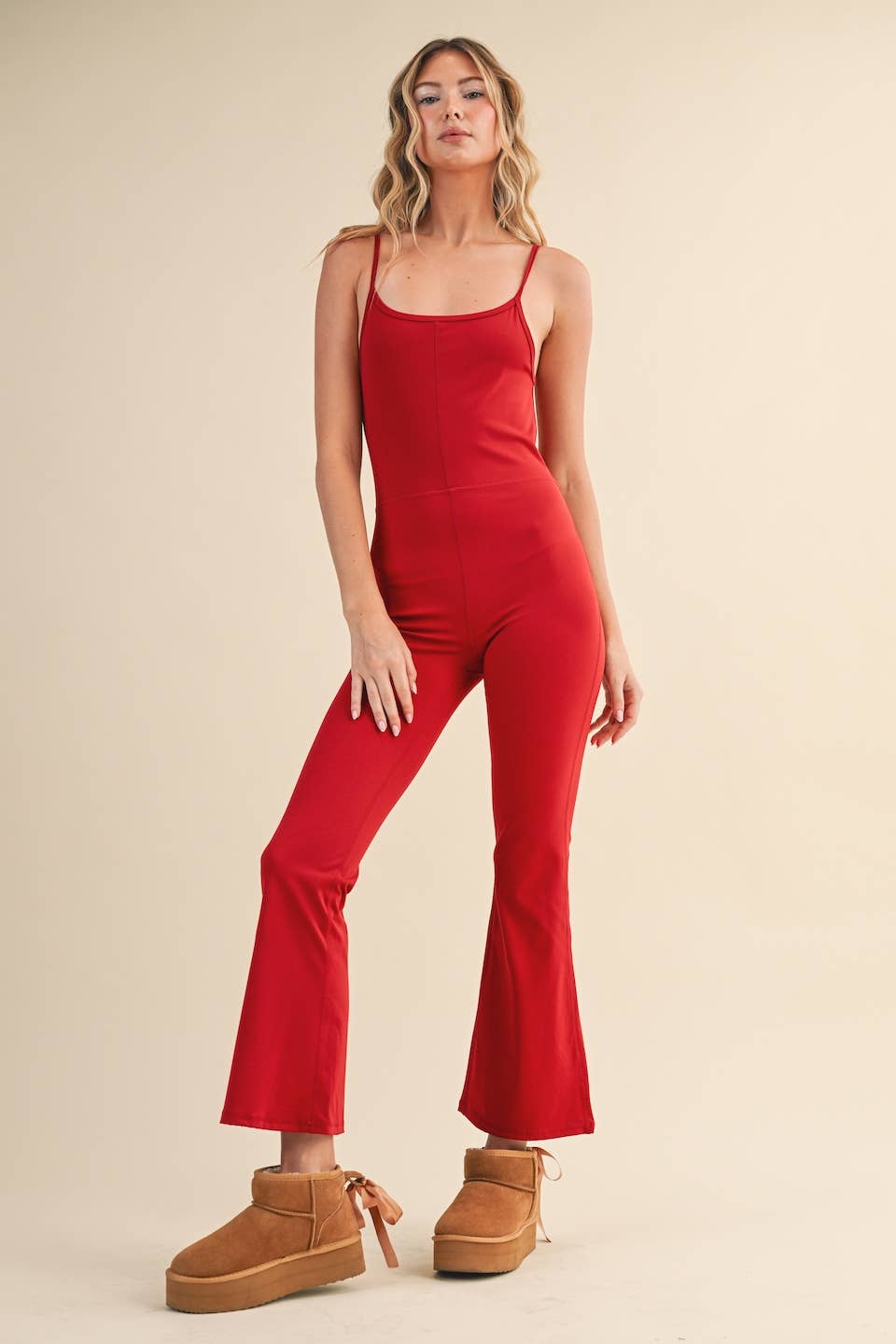 Front view of Woman wearing Kimberly C flare jumpsuit in red with scoop neckline and flared leg.