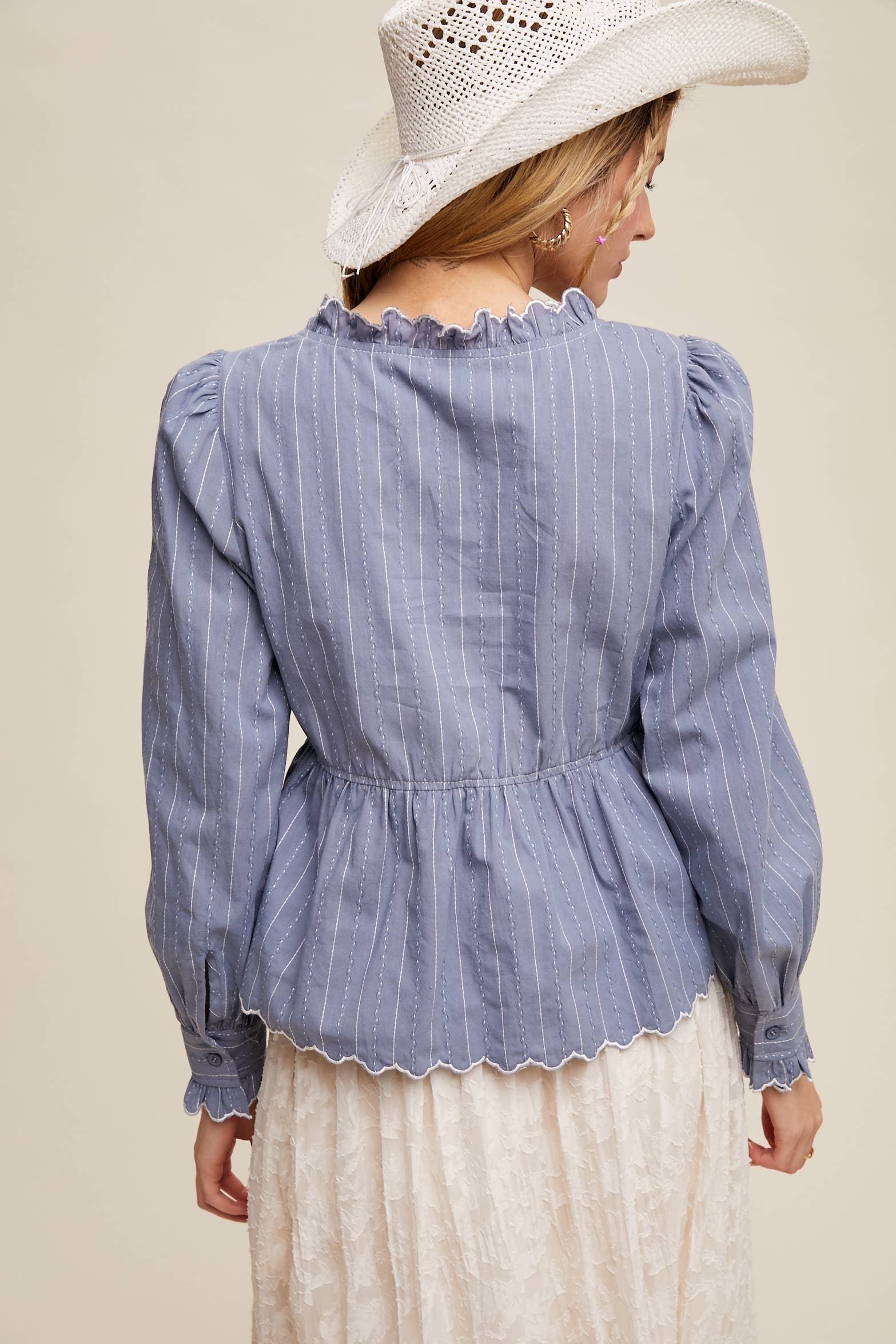 Back view- Side view- Dusty blue pinstripe blouse with ruffled neckline, white rose embroidery, puff long sleeves, button front, and scalloped peplum hem—styled with a white lace skirt and cowboy hat.