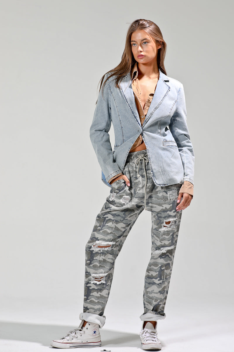 Front view of model styling light-wash denim blazer with tan shirt and distressed camo joggers for a boho-street look.